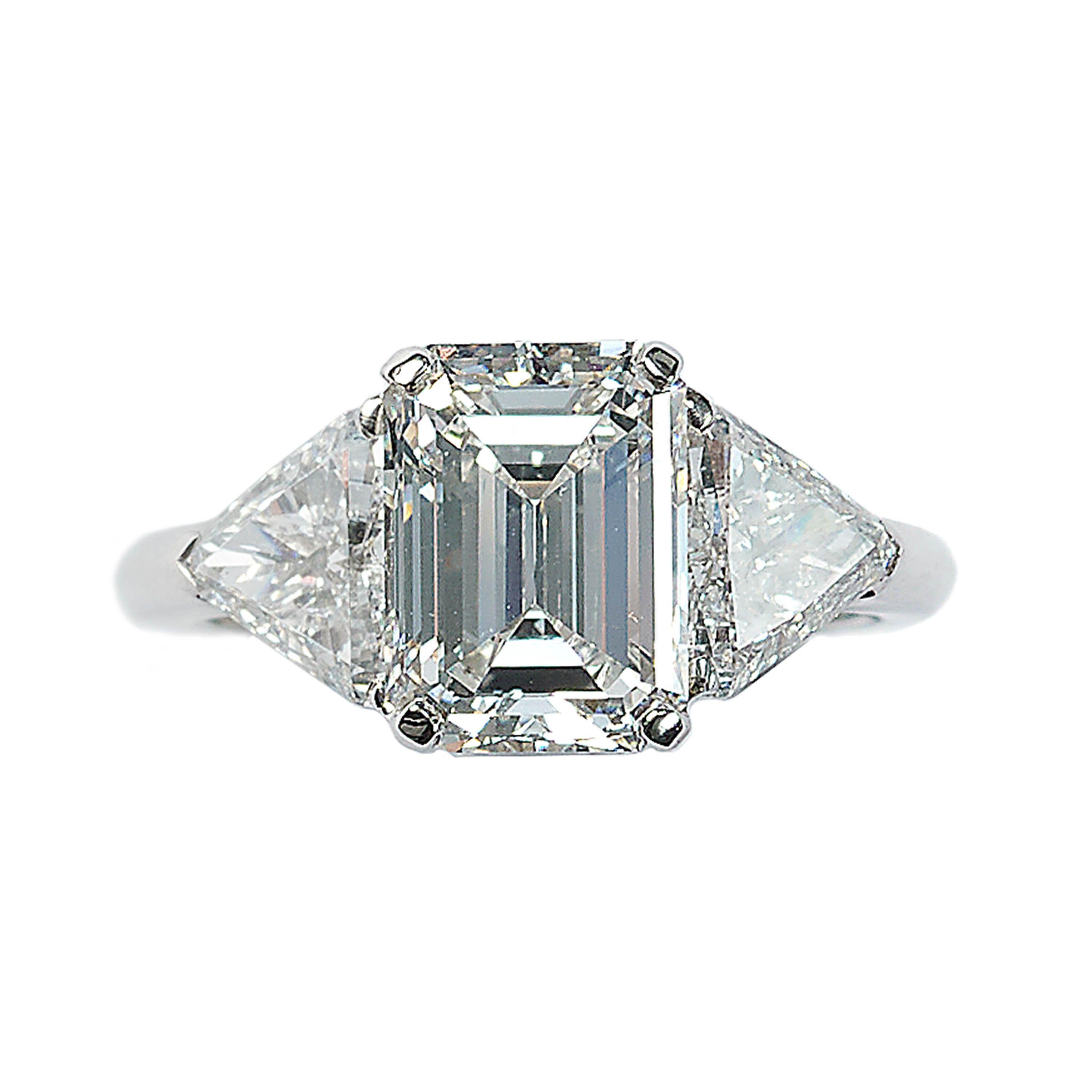 A modern three stone diamond ring, with a central 3.15 carat, E colour, VVS2 clarity emerald-cut diamond, accompanied by GIA certificate number 1226332657, in a four claw setting, with a trilliant-cut diamond, in a three claw setting, in each