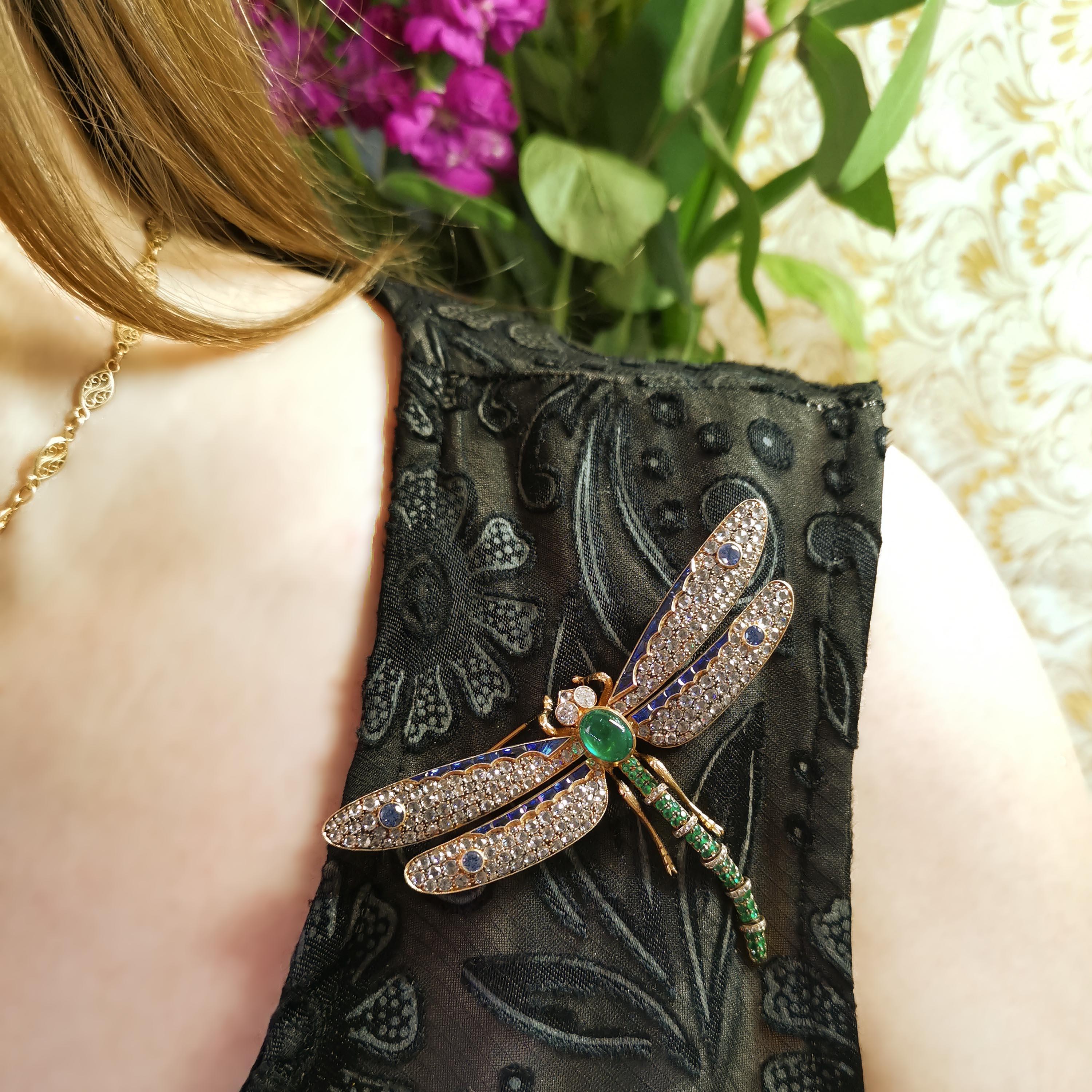 A modern gem set dragonfly brooch, with trembling wings, with an oval cabochon emerald, set in the thorax and round faceted emeralds, pavé set in groups, alternating with bands set with rose-cut diamonds, in the tail, with a rose-cut diamond in the