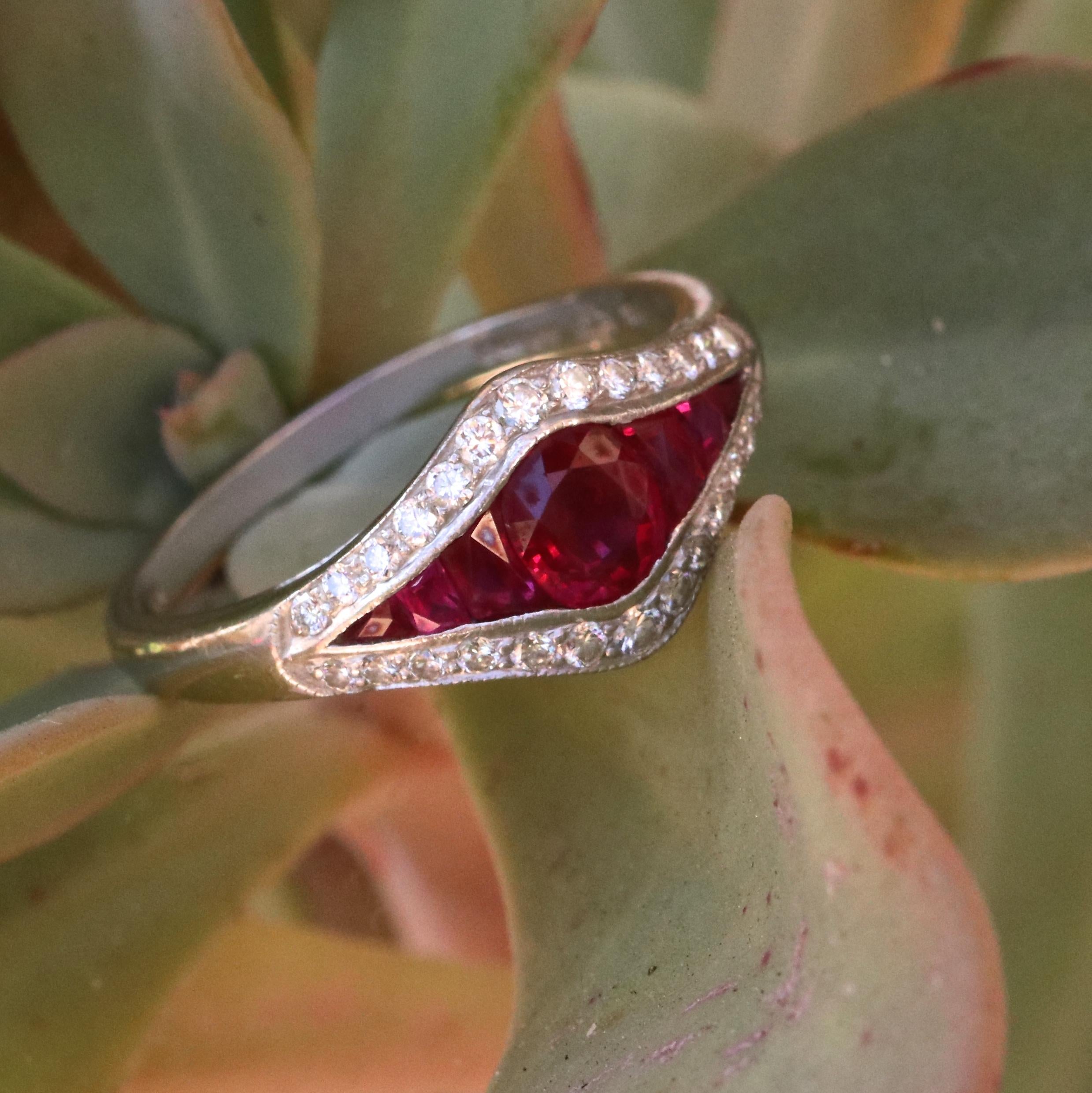Pigeon's blood red rubies and bright white diamonds always delight. This is a modern English ring that showcases 7 faceted rubies weighing approximately 1.15 carats. Accented by 26 round brilliant diamonds graded E-F color, VS+ clarity. Stamped with