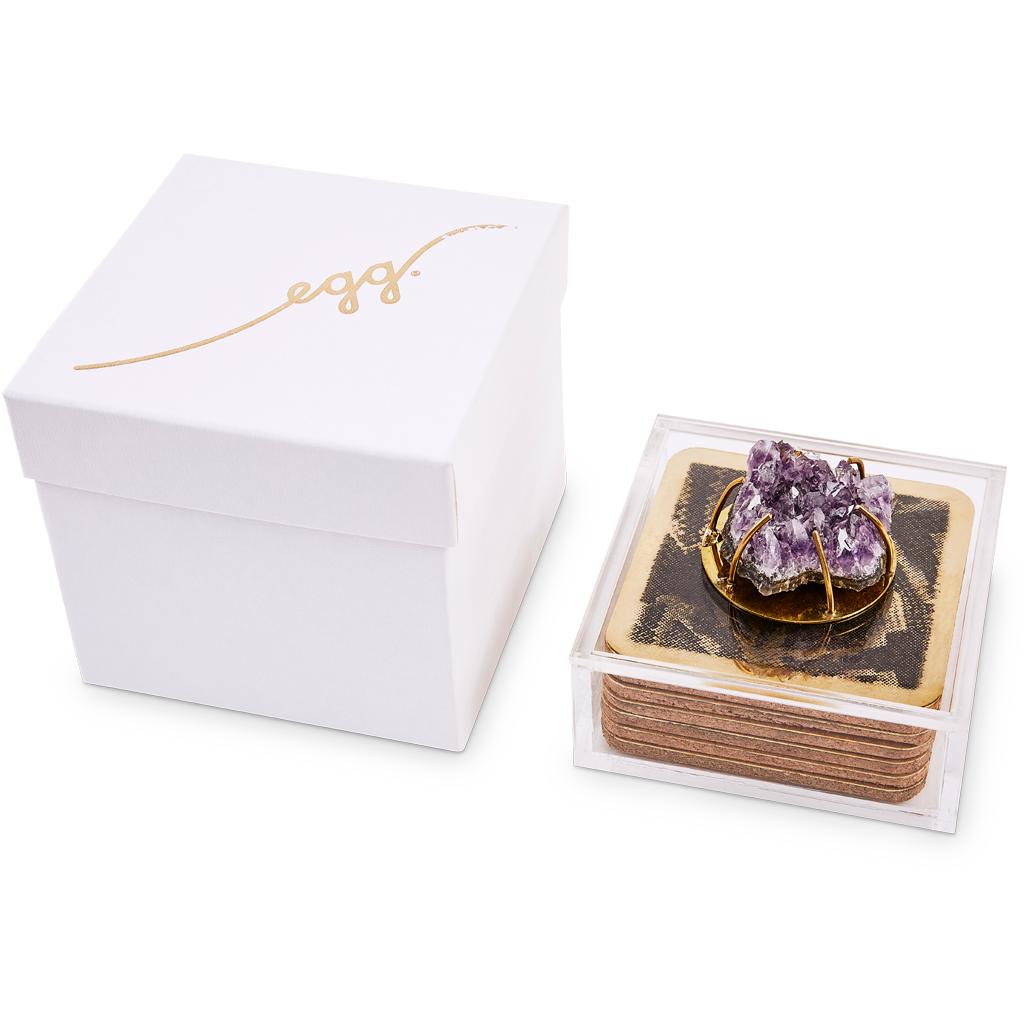 These modern brass coasters are etched with a snakeskin animal pattern and are presented in a Lucite box decorated with a Rose Quartz Agate cabochon. 

This unique and bespoke coaster set is part of the Egg Designs Dawa luxury bar set collection