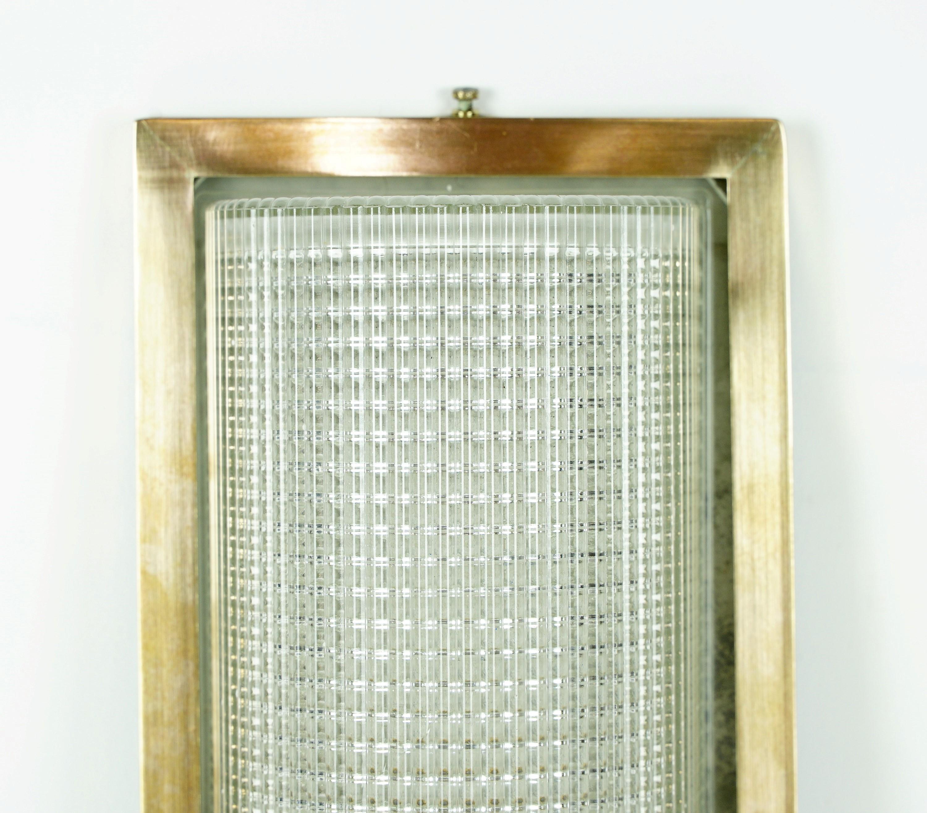 Modern polished brass wall sconce from Europe. The shade is a half cylinder dome with a prismatic Fresnel pattern. The brass frame has some distressing as shown in the images attached.  Cleaned and restored. This will be rewired before shipping.