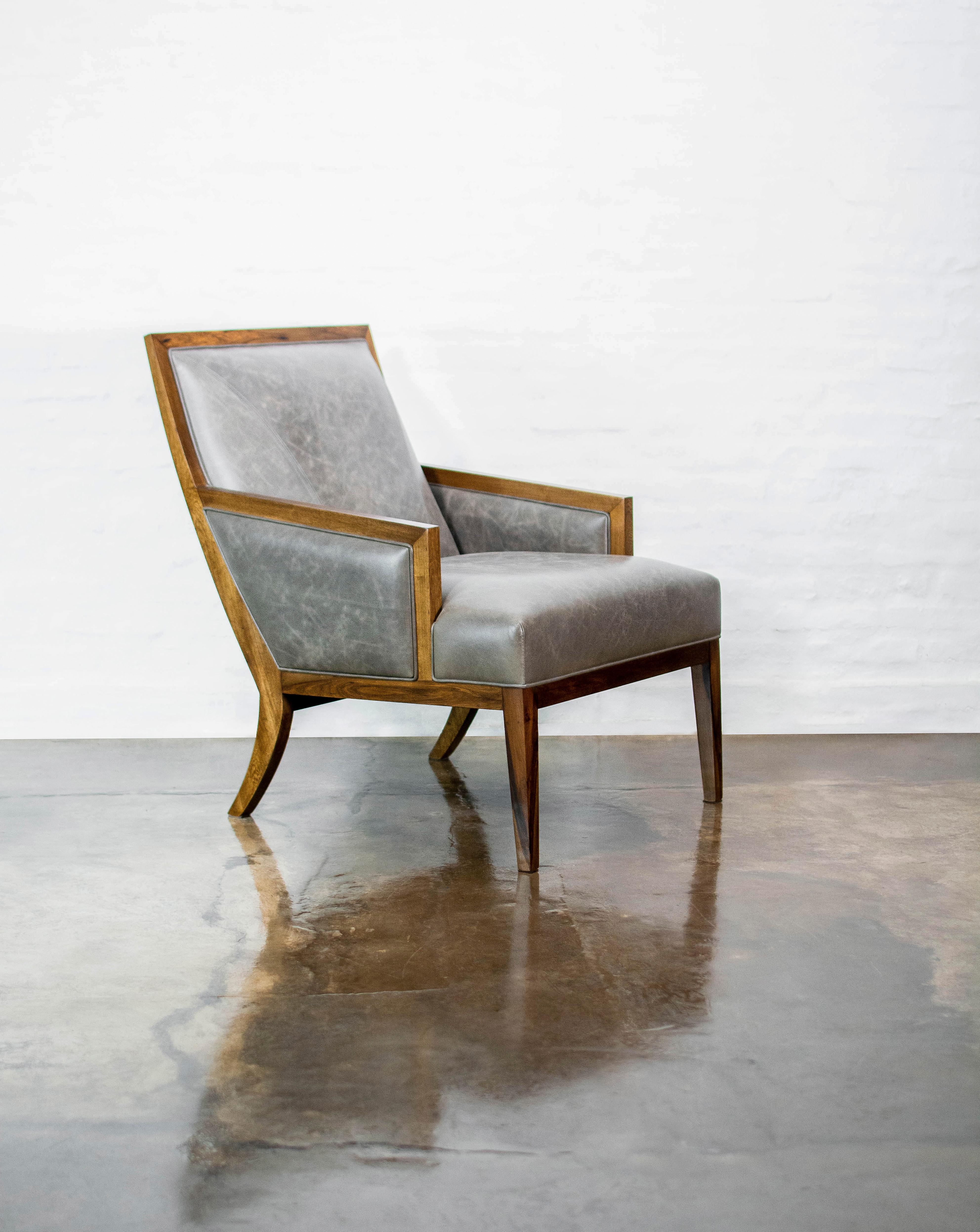 Le fauteuil de salon Belgrano s'inspire du design moderniste du milieu du XXe siècle et présente un design ergonomique qui peut être personnalisé grâce à des coussins d'appoint. Elle présente un détail de points décoratifs qui part du coin supérieur