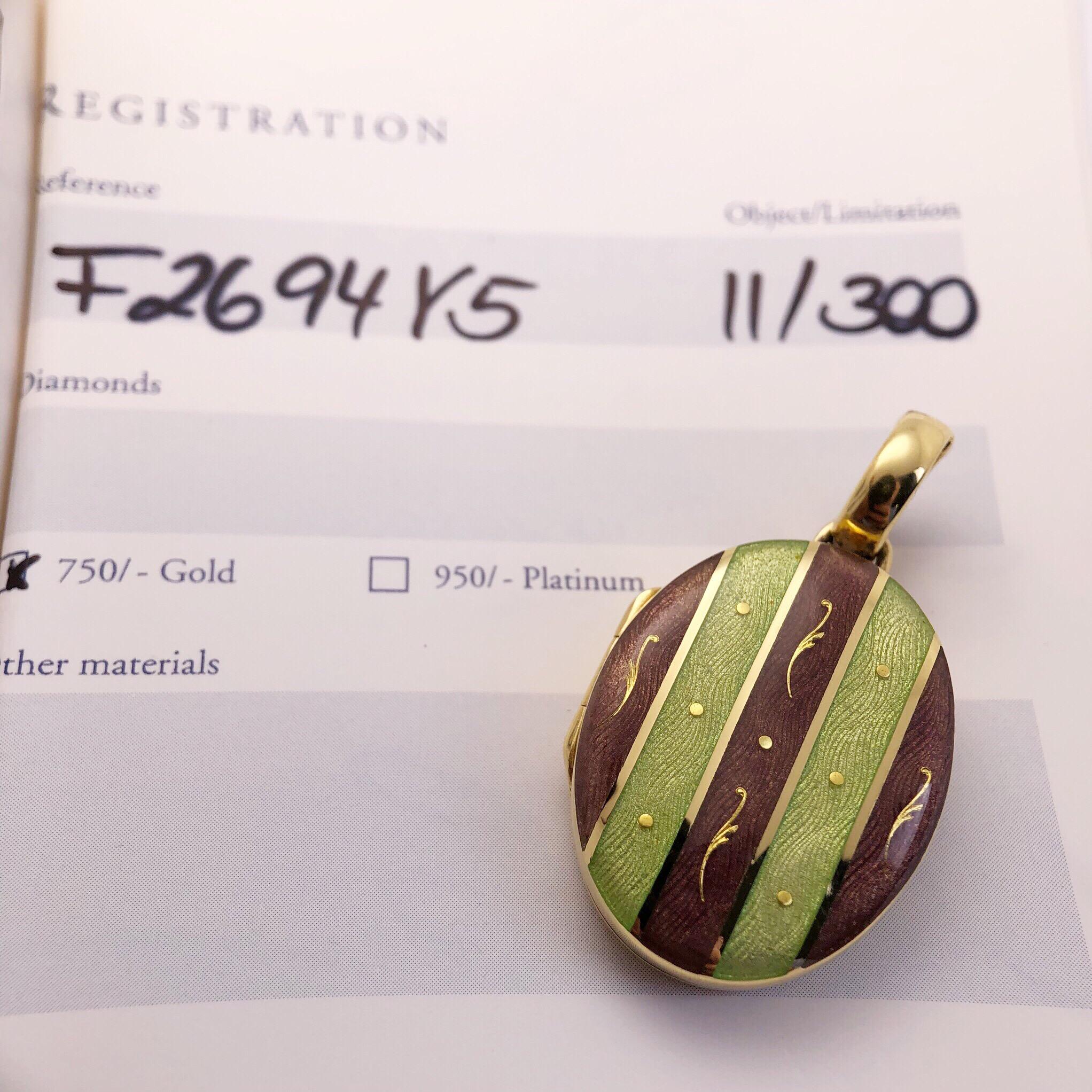 This Modern Faberge 18 Karat Yellow Gold oval locket is adorned with Purple and Green Guilloché Enamel stripes. The 18 Karat yellow gold bale opens allowing you to attach the locket on to various strands. The locket opens and contains two removable