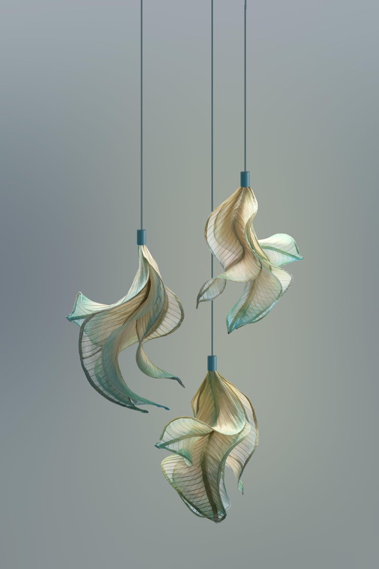 Sirenetta; inspired by a sea siren. 

When the sun hits the horizon, imagine it gracefully swimming to the water surface to catch a glimpse of her lover. This suspension lamp is made from banaca (banana-abaca) textile, sculpted to evoke undulating