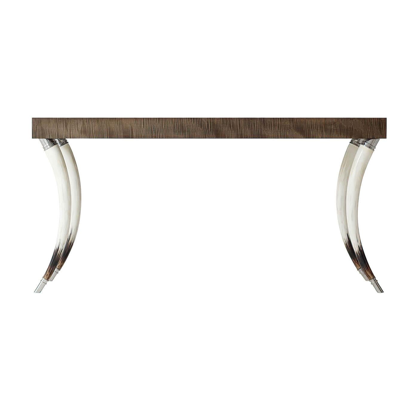 A modern platinum sycamore veneered and faux horn console table, the thick rectangular top on curved naturalistically hand-painted faux horn legs with stainless steel capitals and feet.

Dimensions: 64
