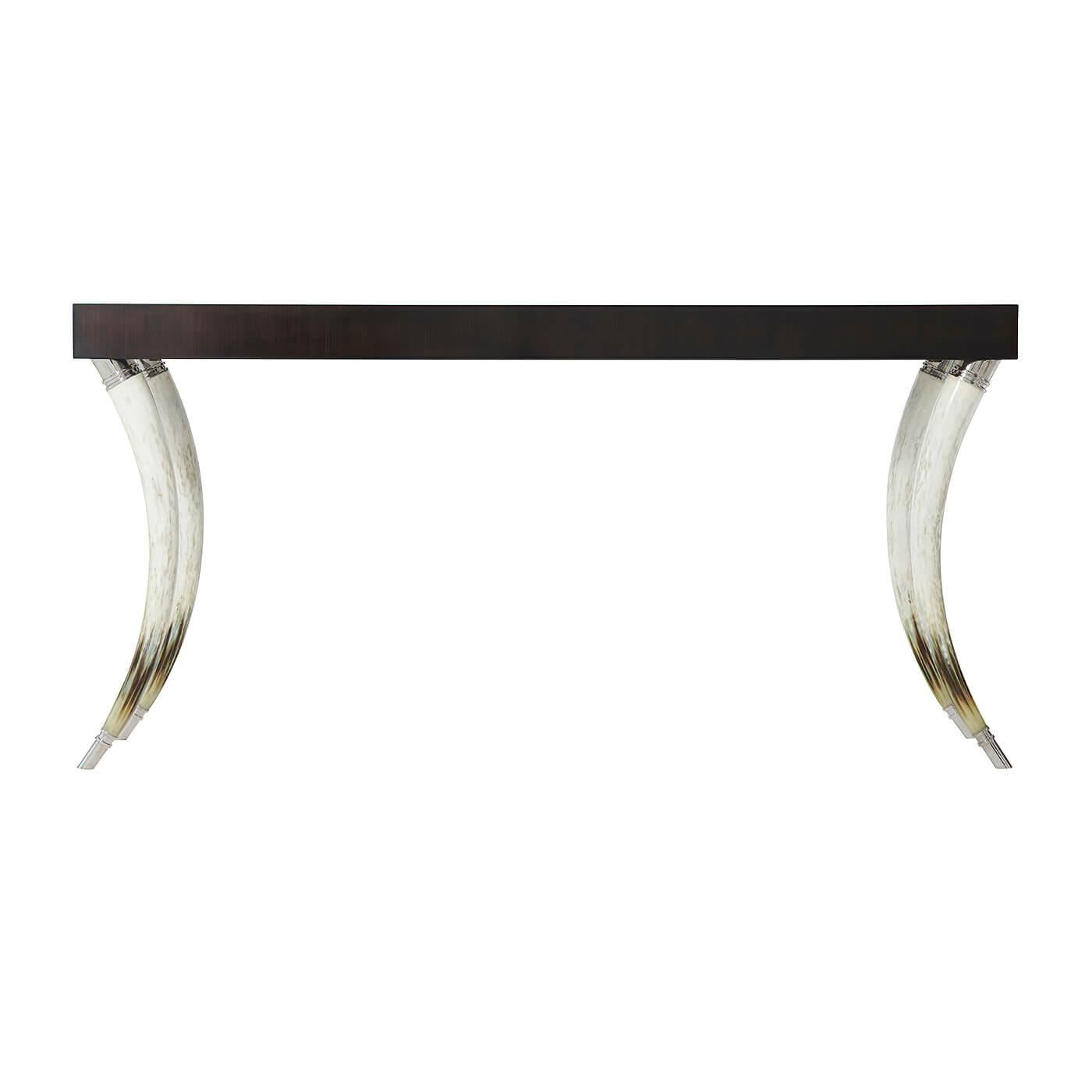 A modern ebonized Hyedua veneered and faux horn console table, the thick rectangular top on curved naturalistically hand-painted faux horn legs with stainless steel capitals and feet.

Dimensions: 64