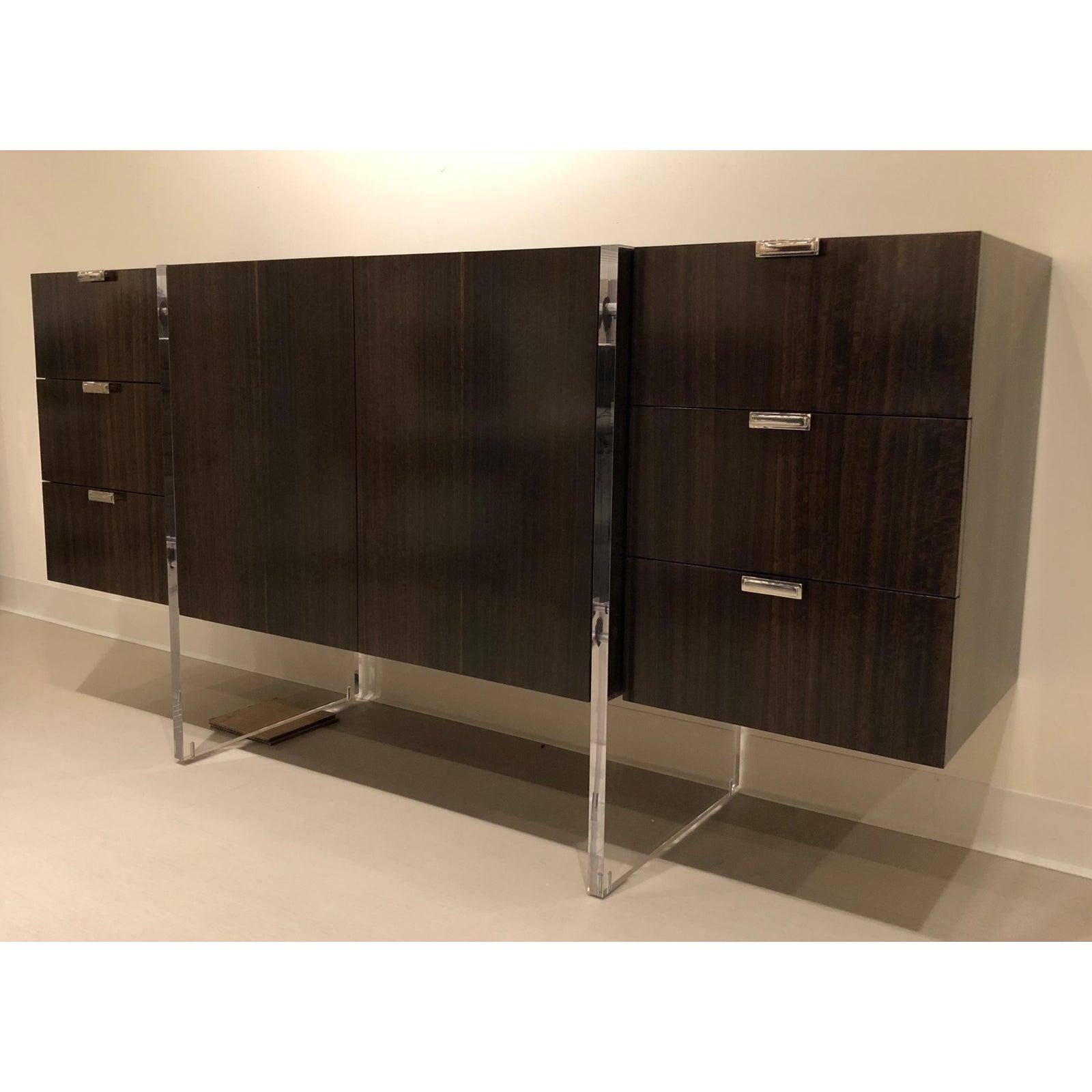 Showroom New. This modern cabinet or sideboard has fumed figured Eucalyptus Veneer, Acrylic slab supports and six soft closing drawers with stainless steel handles. The center portion cabinet has one adjustable shelf.