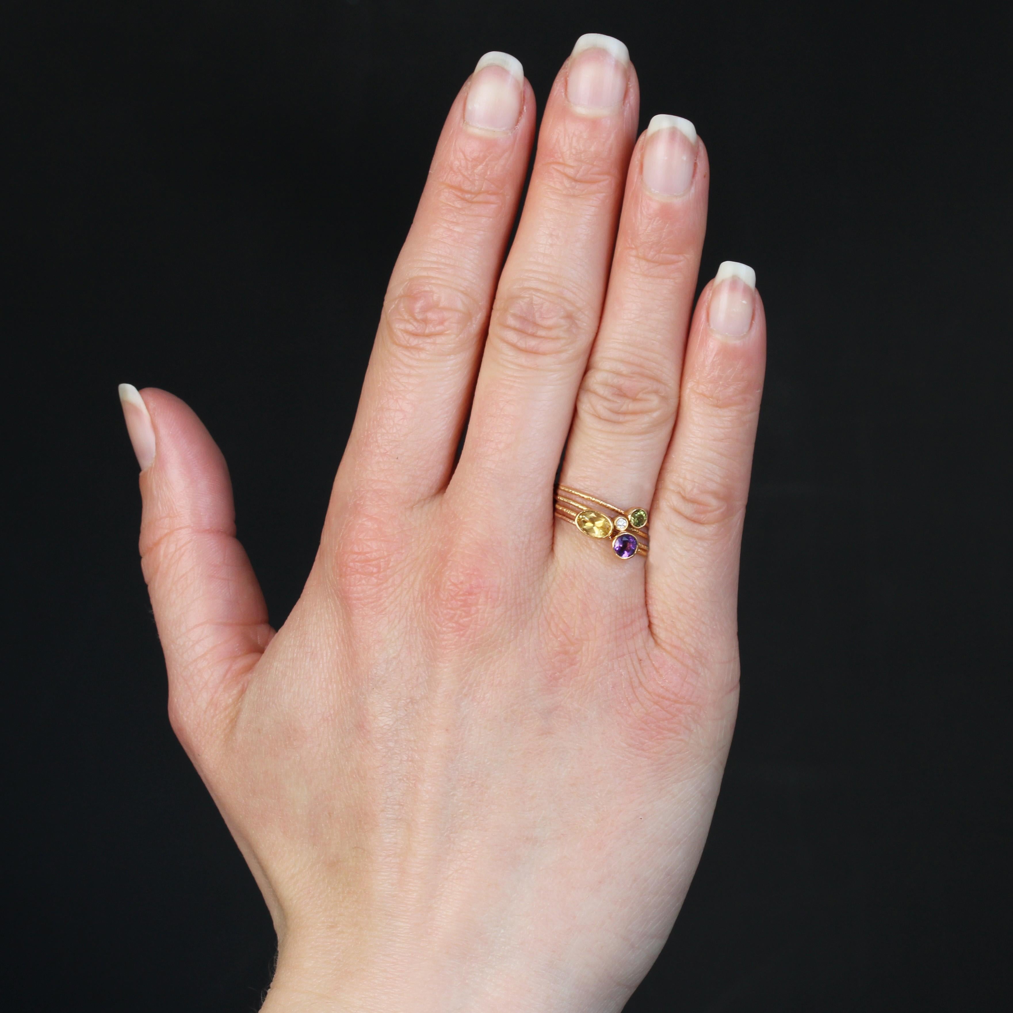 Ring in 14 karat rose gold.
Second-hand Gold ring, it is composed of 4 rings of gold amati retained between them not a mobile gold bar. Each ring is set closed round or oval of an amethyst, a citrine, a diamond and a peridot.
Height of the gold bar