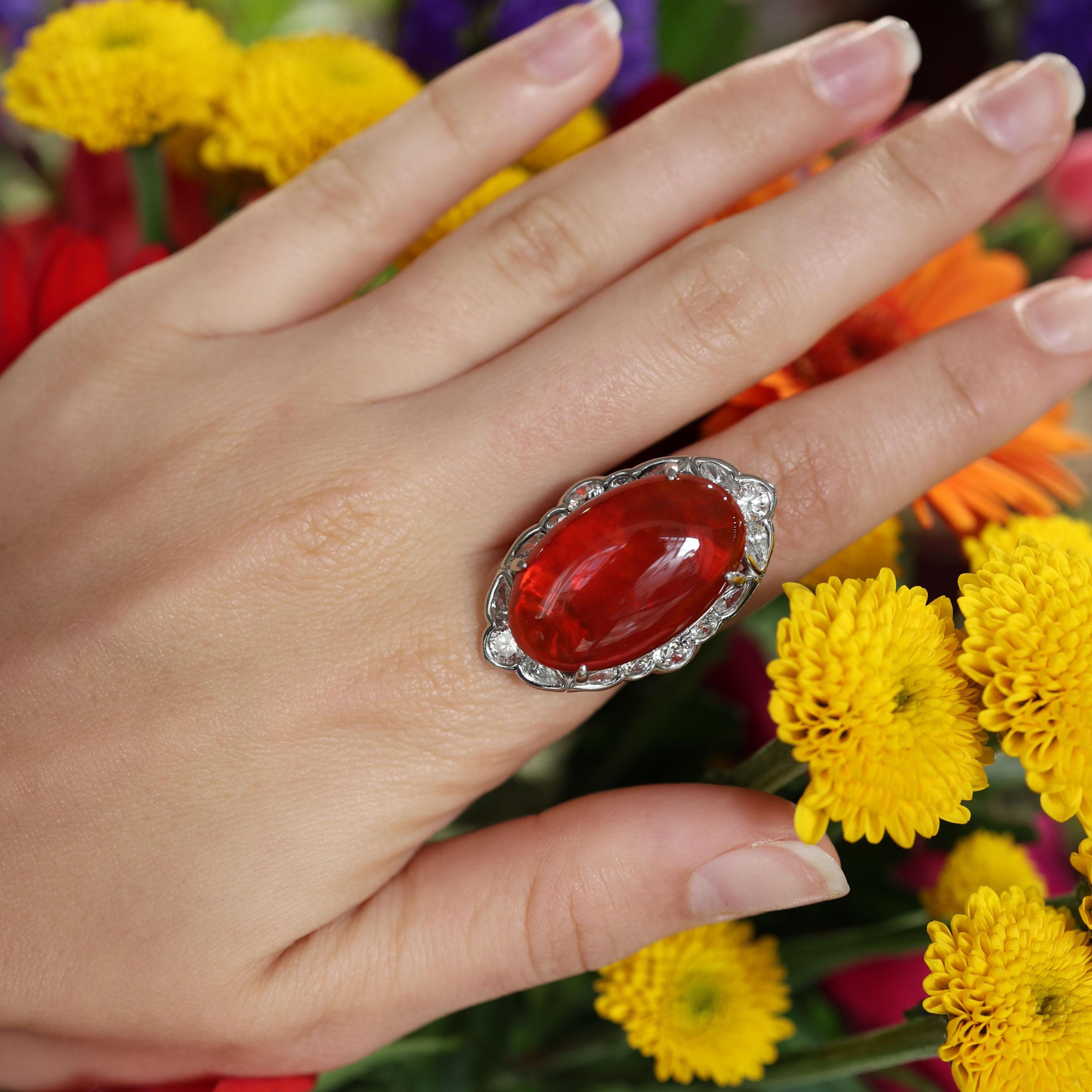 Ein moderner Feueropal- und Diamant-Cluster-Ring, besetzt mit einem großen, ovalen Feueropal im Cabochon-Schliff, von satter, orangefarbener Farbe mit Farbspiel, mit einem geschätzten Gewicht von 18.00 Karat, in einer Vier-Krallen-Fassung, umgeben