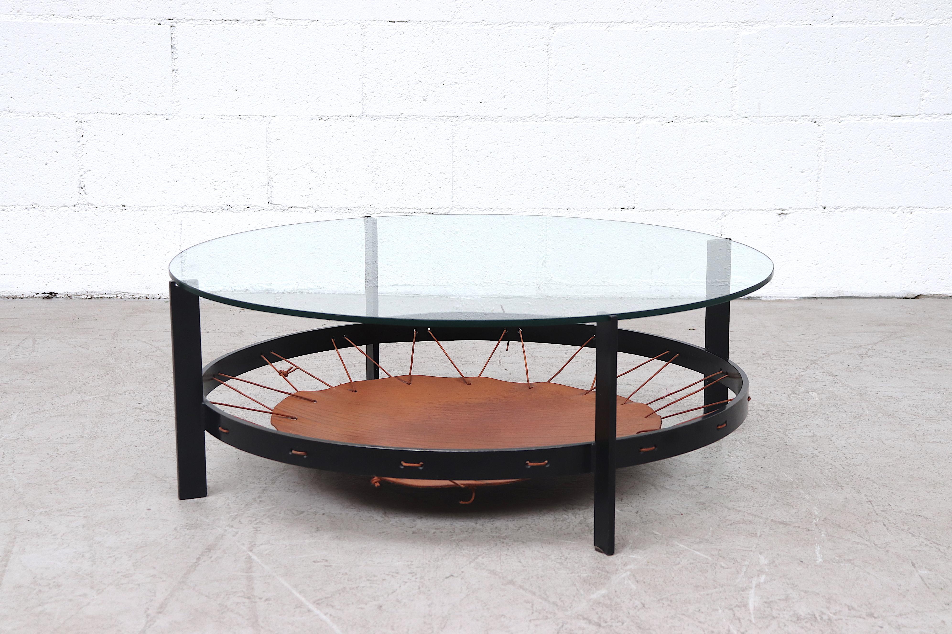 Amazing black enameled iron coffee table with inset glass and leather trampoline magazine rack with nice patina. In original condition with some enamel loss and light scratching.
 