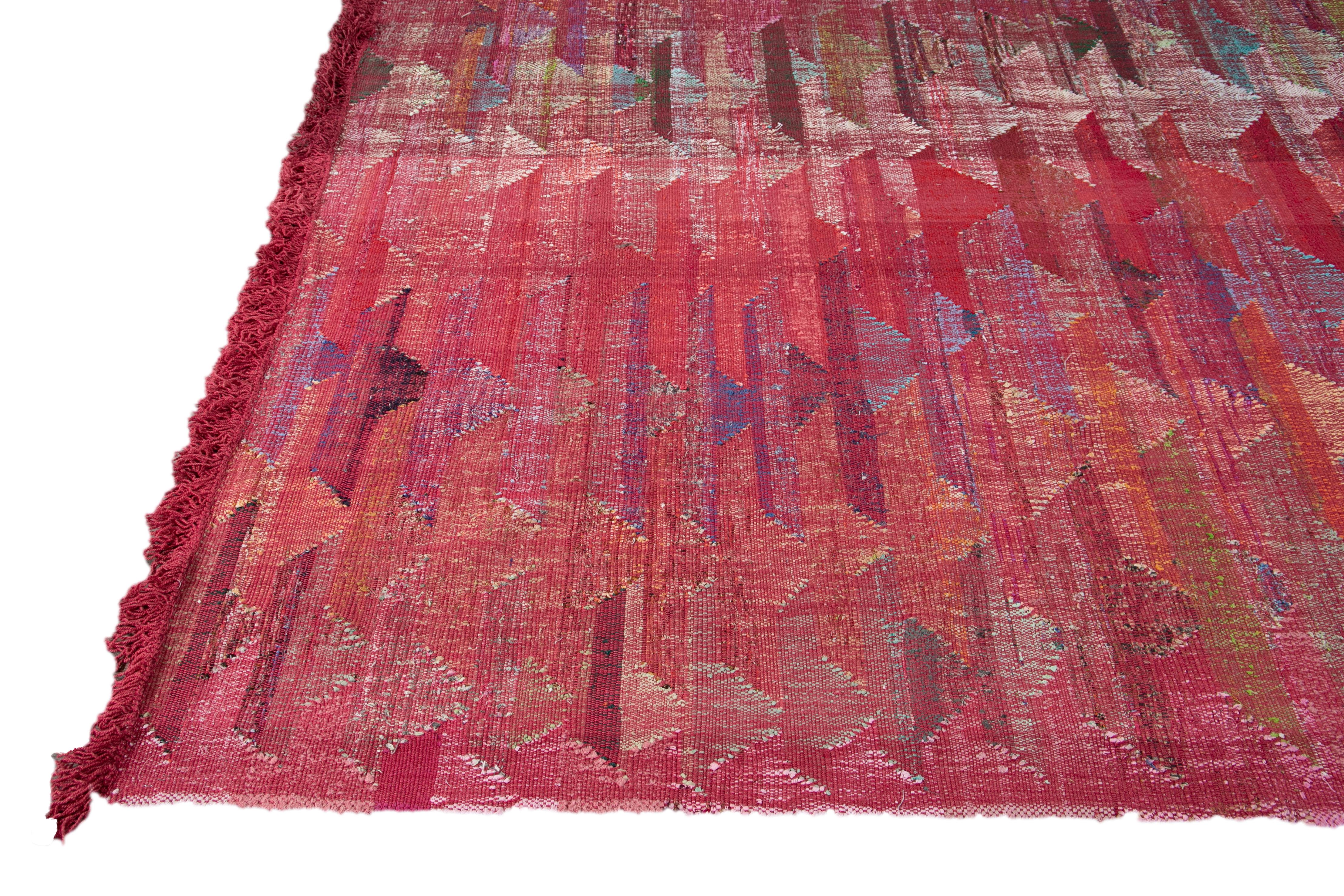 Beautiful Modern Kilim Flat-weave handmade wool rug. This piece of art has a red field and multi-color accents in a gorgeous geometric abstract design.

This rug measures: 10'1