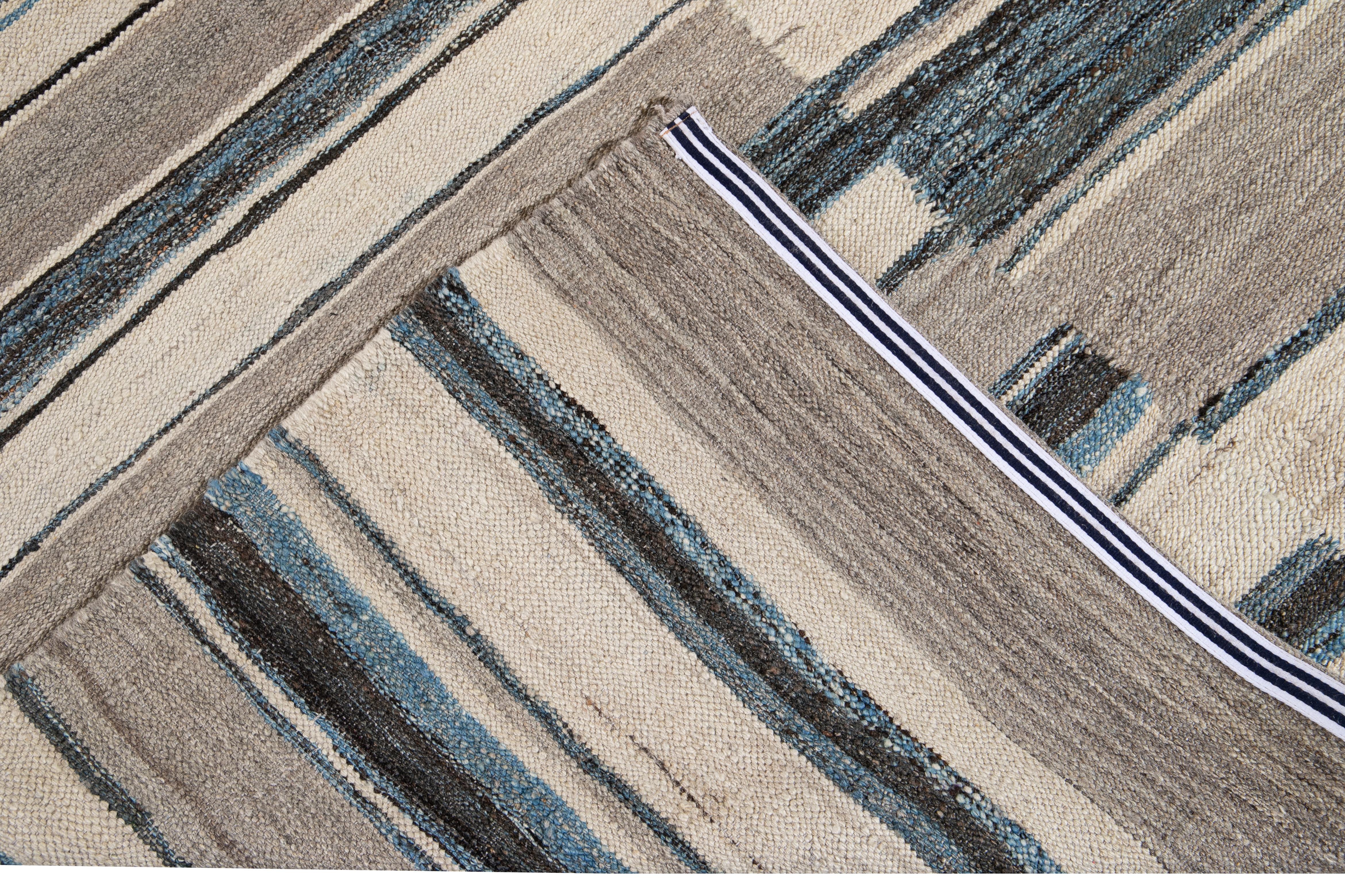 Beautiful modern flat-weave handmade wool rug. This Kilim rug has a beige field with accents of blue and brown in a gorgeous geometric expressionist design.

This rug measures: 9' x 12'1