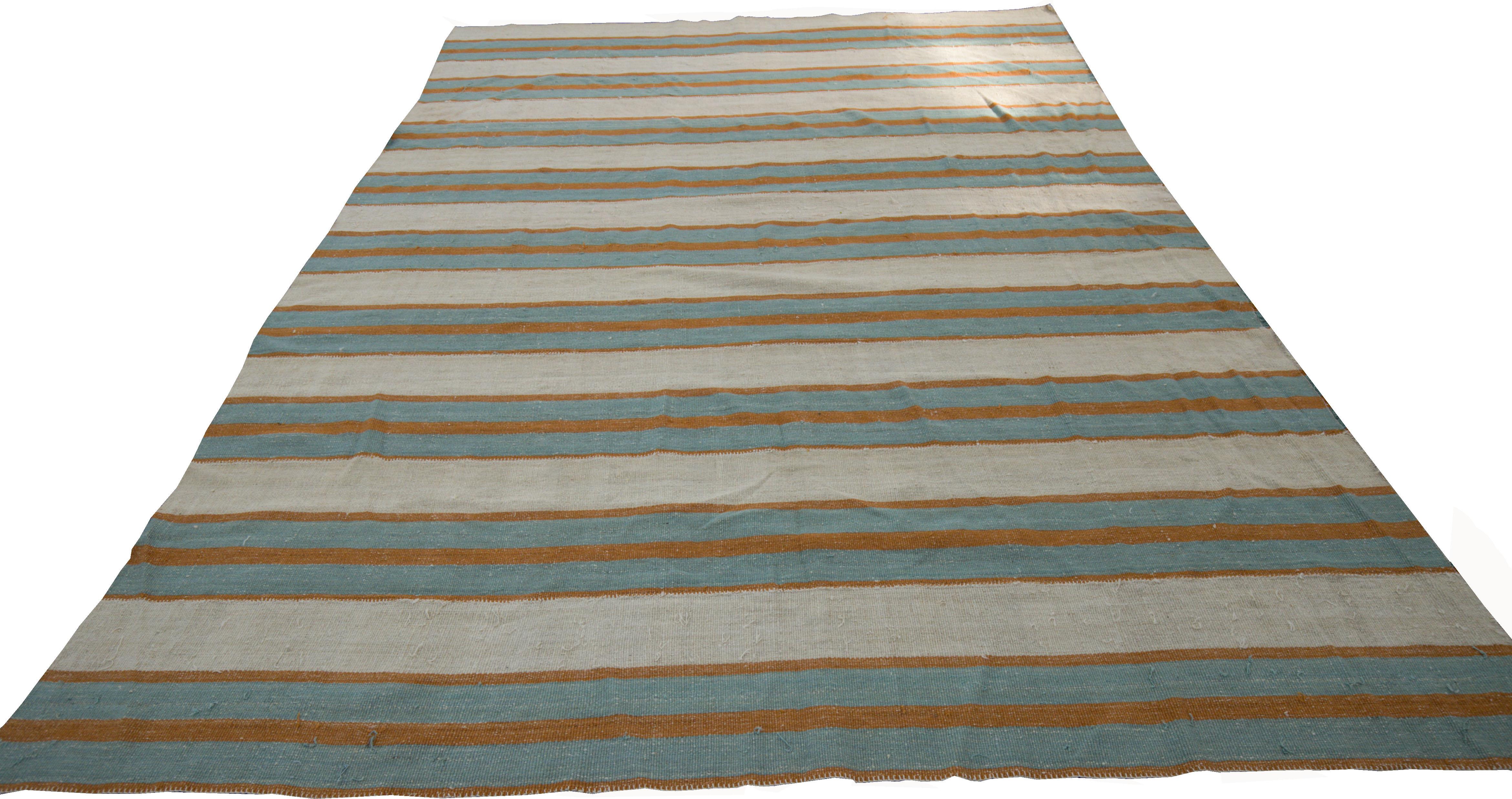 A new production Persian rug handwoven from the finest sheep’s wool and colored with all-natural vegetable dyes that are safe for humans and pets. It’s a traditional Kilim flat-weave design featuring a lovely ivory field with blue and orange