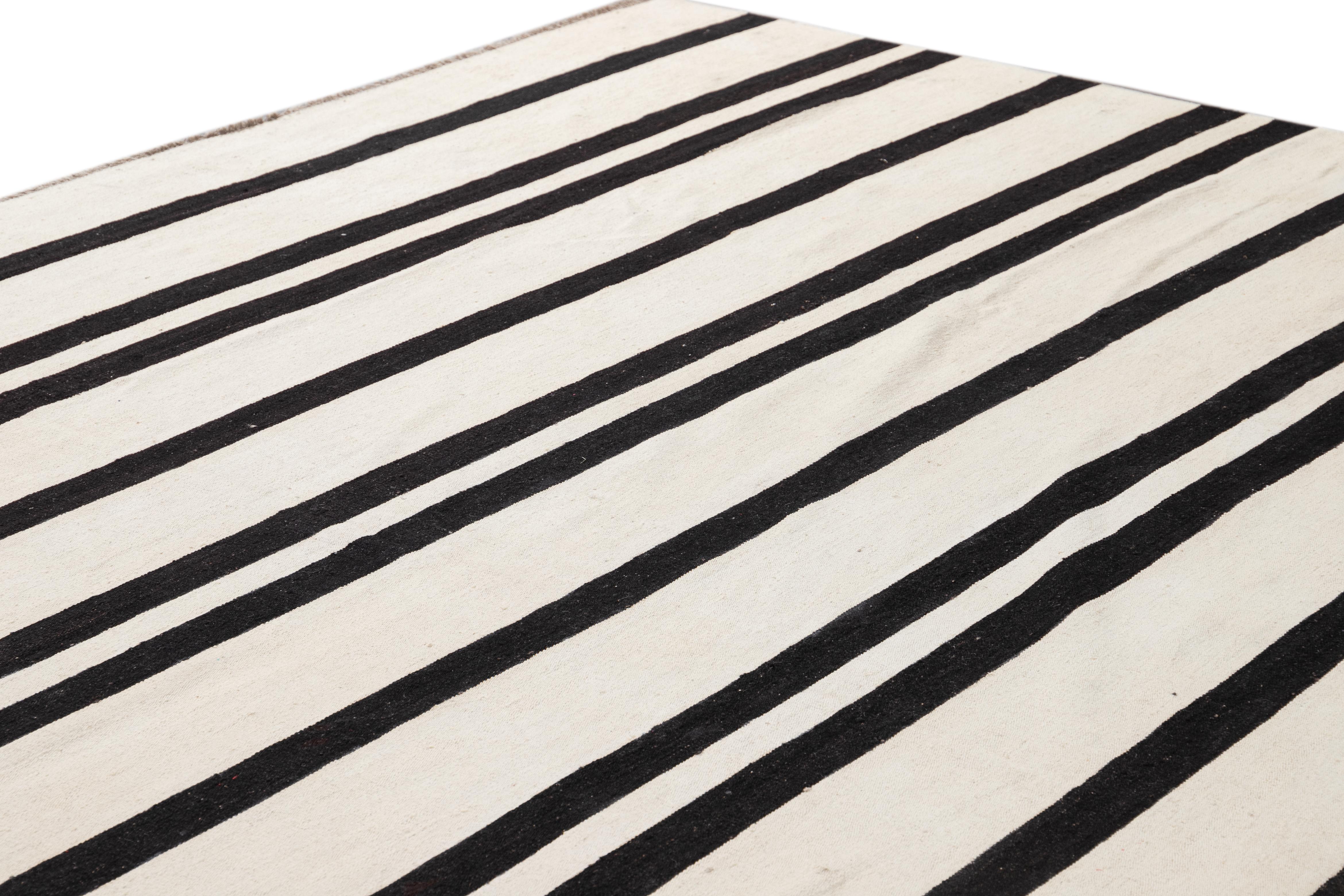 An oversized flatweave rug with a modern black and white stripe design. Made from quality wool for a long-lasting addition to any space.

This rug measures 14' 3