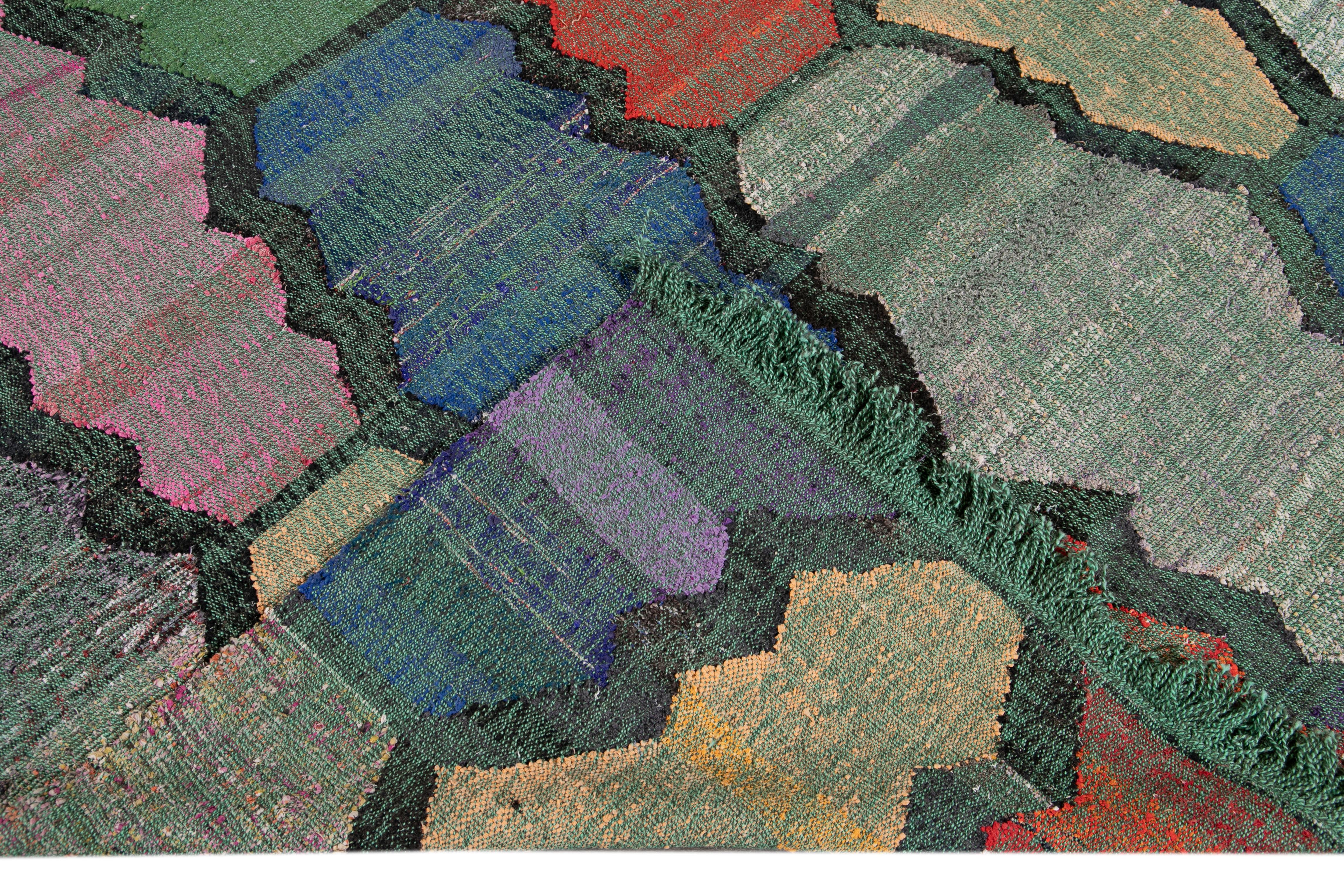 Schöner moderner flachgewebter Kilim-Wollteppich mit grünem Feld. Dieses Kunstwerk hat mehrfarbige Akzente in einem wunderschönen geometrischen abstrakten Design.

Dieser Teppich misst: 8' x 12'1