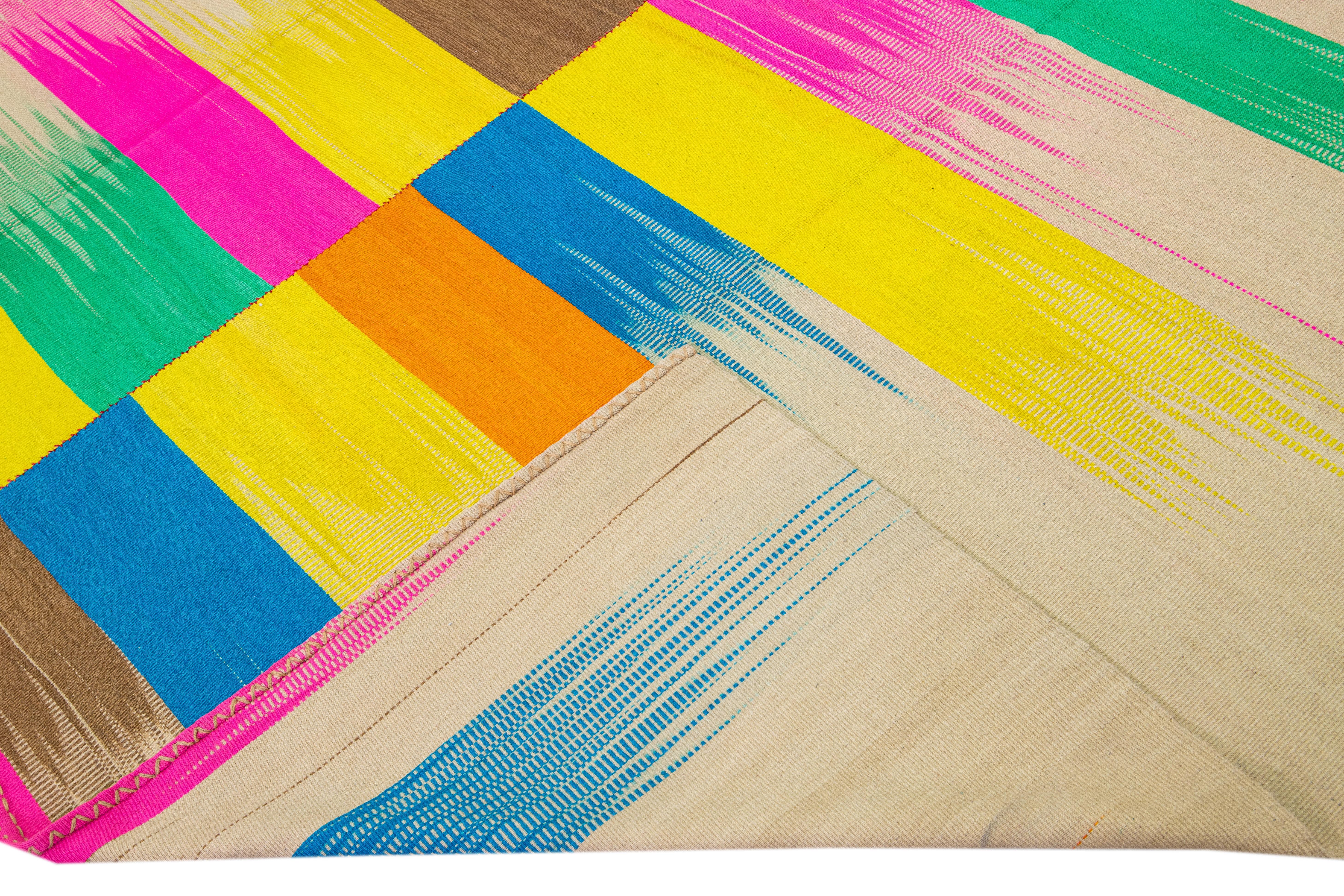 Magnifique tapis moderne Kilim en laine tissée à plat avec un champ beige. Cette œuvre d'art présente des couleurs vives et multicolores dans un magnifique motif abstrait rétro.

Ce tapis mesure : 9'10