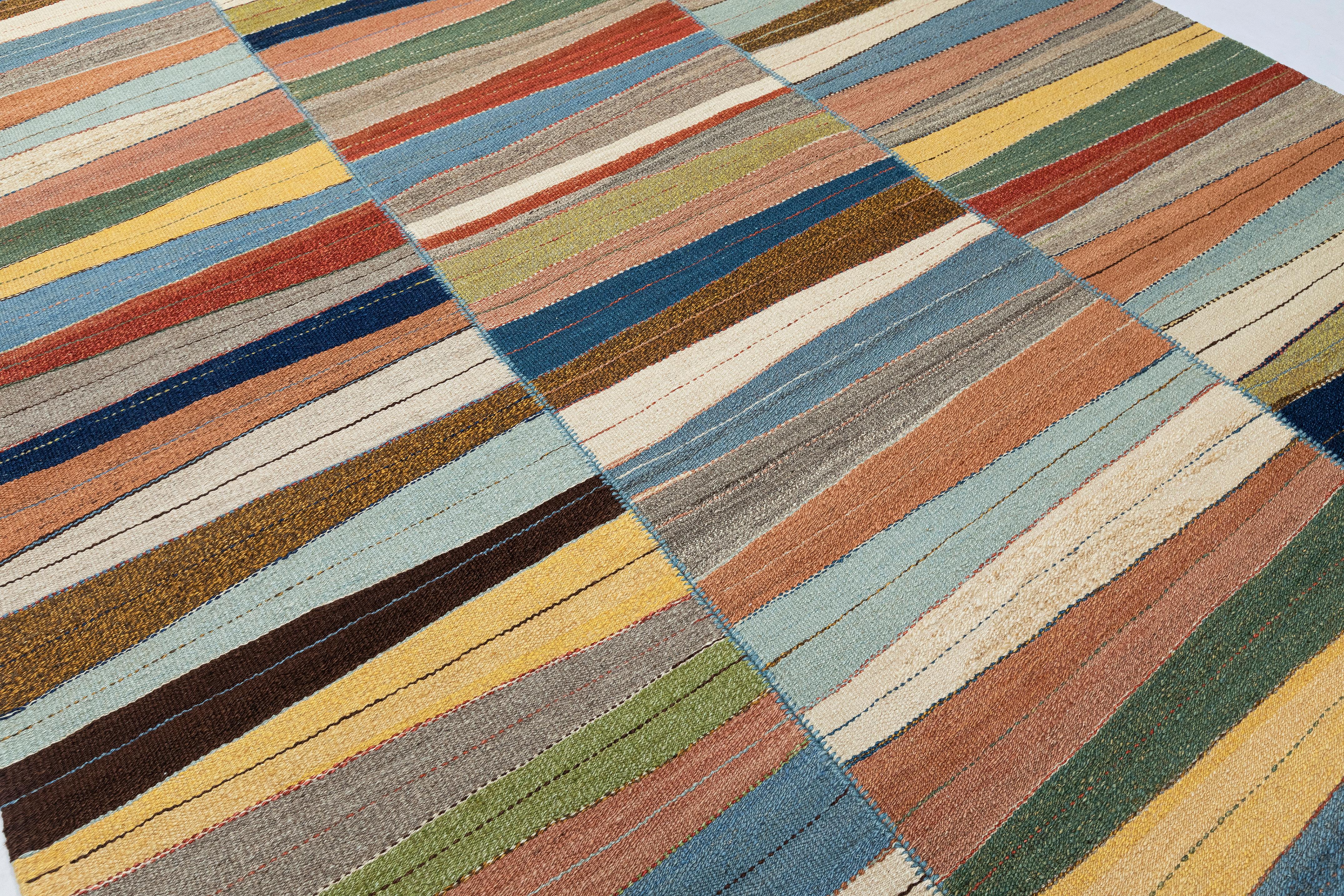 Esta moderna y vibrante alfombra kilim de tejido plano presenta un diseño ondulado multicolor que aporta movimiento dinámico y expresión artística a cualquier interior. Tejida a mano por expertos con lana 100%, refleja la precisión y la habilidad de