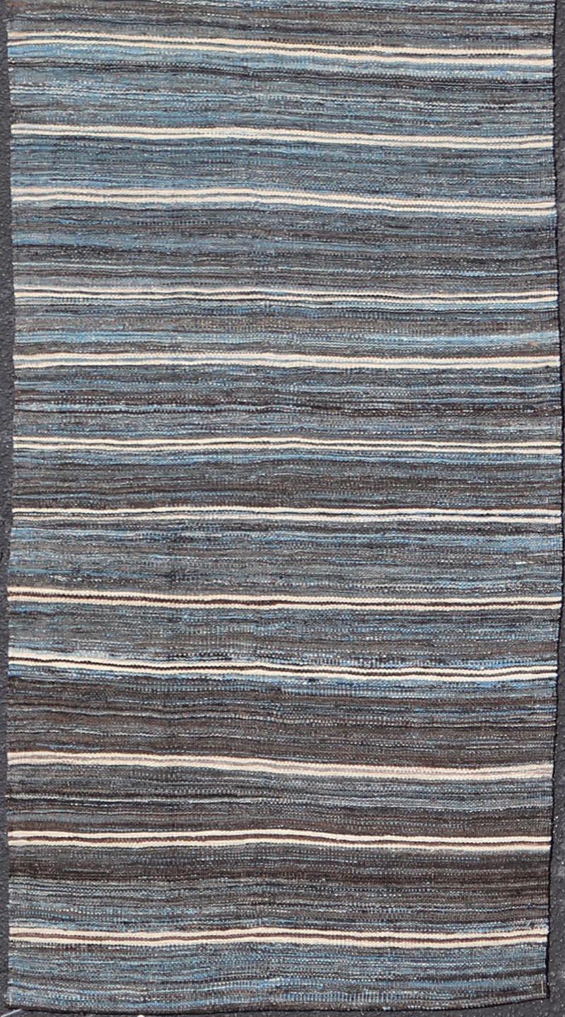 This flat-weave tribal kilim has been hand-woven. The rug features a horizontal stripe design, rendered in Charcoal, Ivory, Browns and Blues; making this rug a superb fit for a variety of classic, modern, casual and minimalist interiors.

Modern