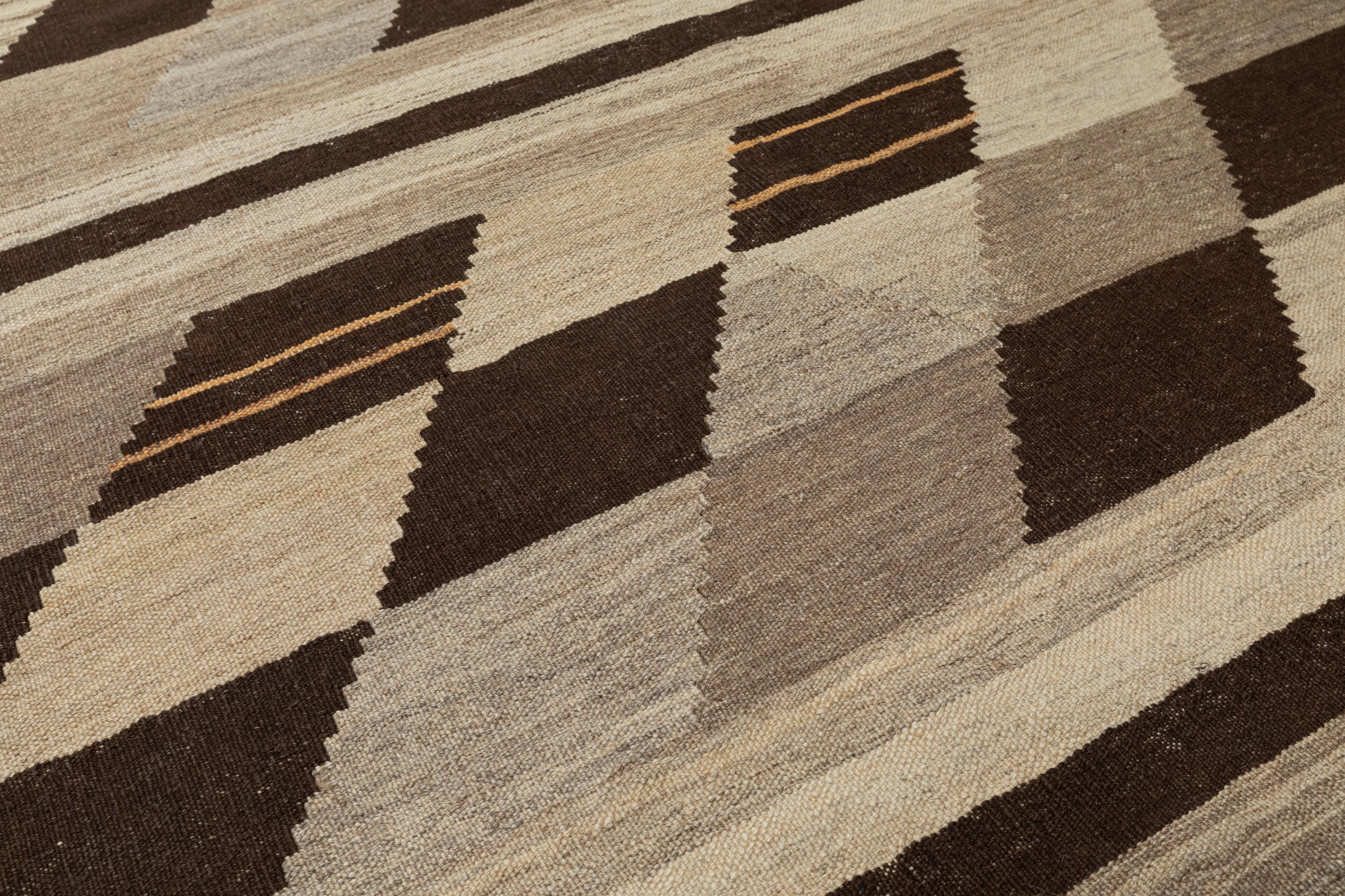 Questo tappeto kilim a tessitura piatta intrecciata a mano presenta un sorprendente motivo geometrico chevron disposto in file orizzontali, offrendo un ritmo visivo audace che affonda le sue radici nell'artigianato. Realizzato in lana naturale e