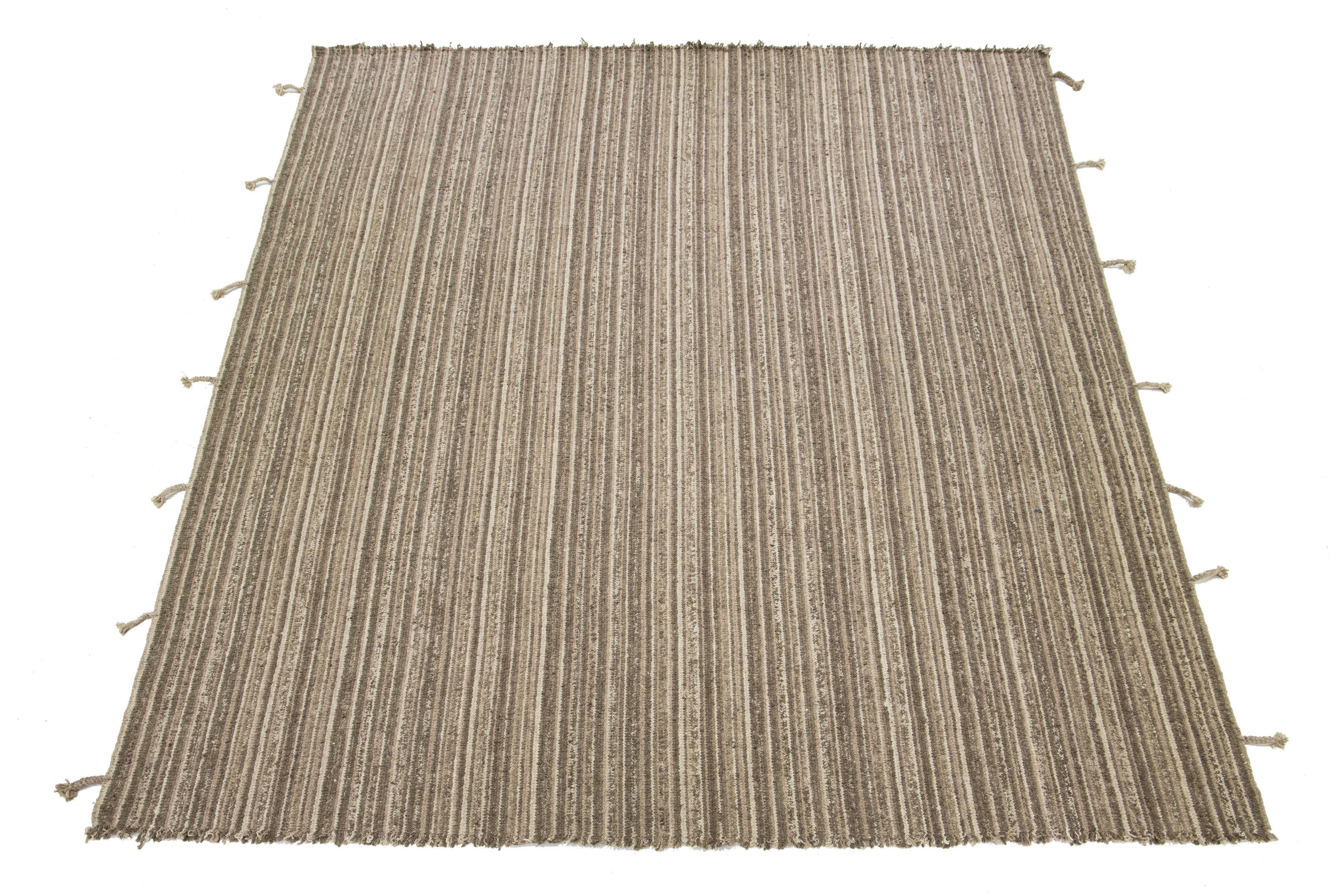 Questo tappeto kilim contemporaneo a trama piatta presenta un campo di colori beige, marrone e marrone con un disegno geometrico all-over e frange sui lati.

Questo tappeto misura 12'1