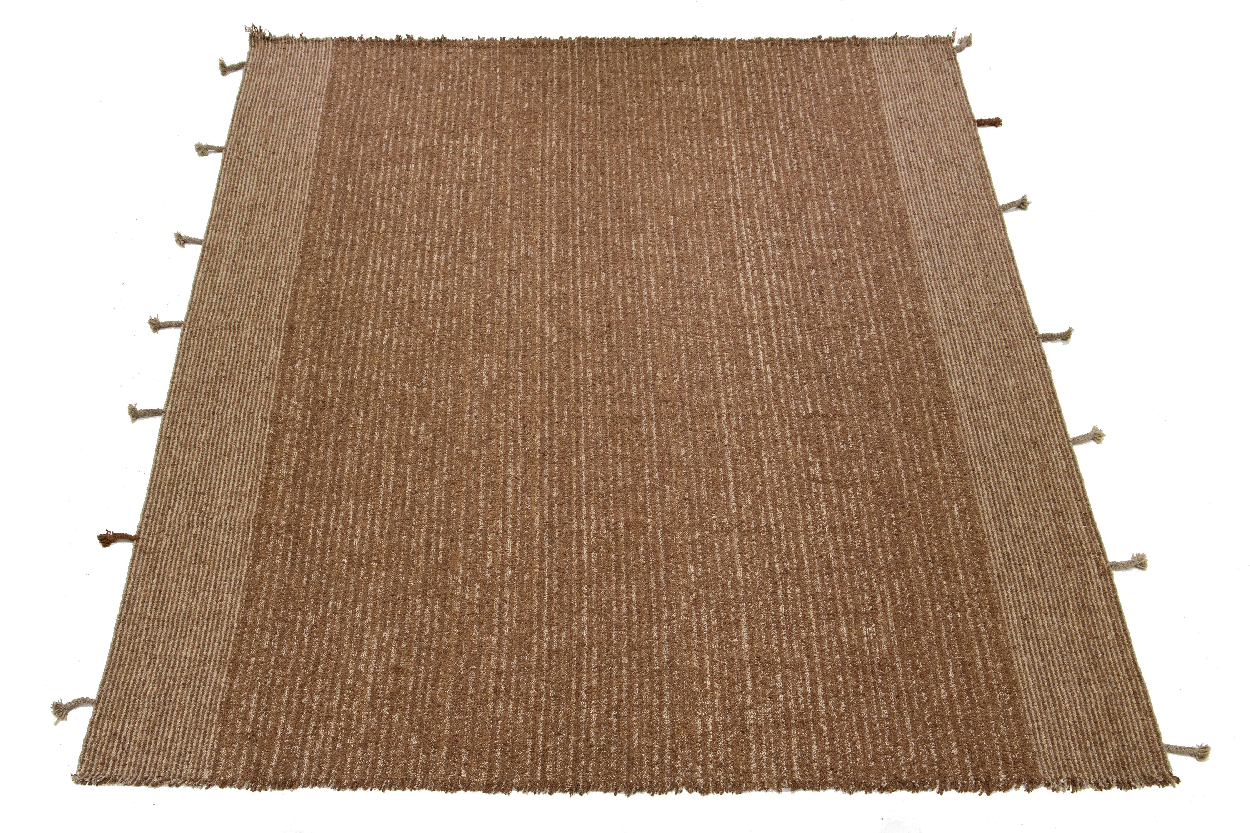 Una alfombra kilim contemporánea de tejido plano que presenta un campo de color marrón con un diseño geométrico integral y flecos.

Esta alfombra mide 12'1