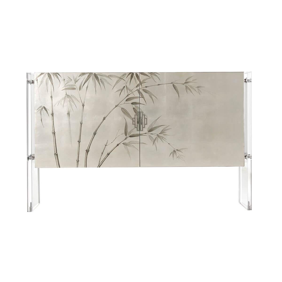 A modern cabinet with hand silver-leafed Grisaille painted bamboo door panels, the case wrapped with exotic Sycamore veneers, appears to be floating as its suspended between acrylic slab supports and stainless steel fittings and handles. The