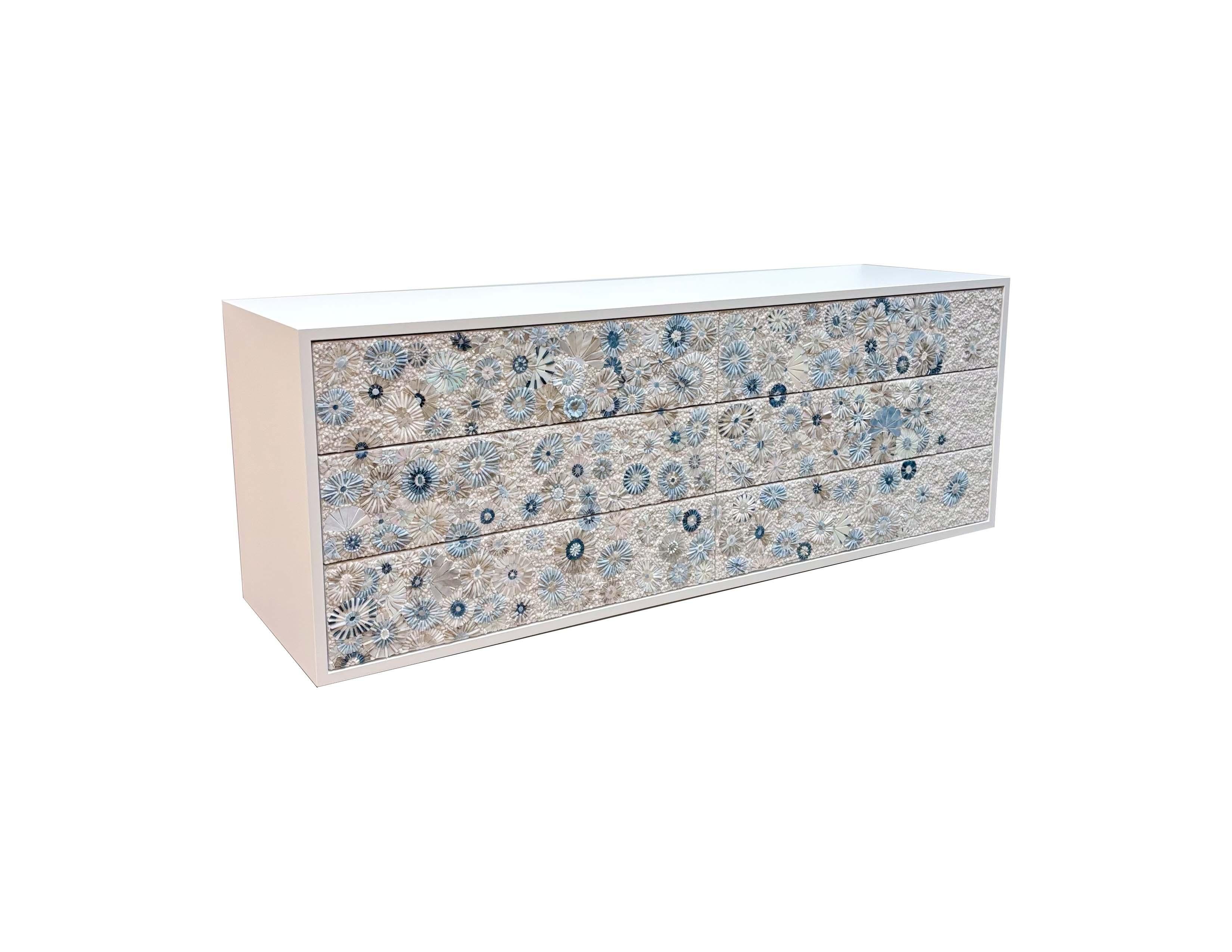 La cassettiera galleggiante moderna a sei cassetti con mosaico di fiori selvatici di Ercole è caratterizzata da un corpo in lacca bianca, montato a parete tramite un'asola francese. Ha sei cassetti con chiusura a sfioramento, con frontali in mosaico