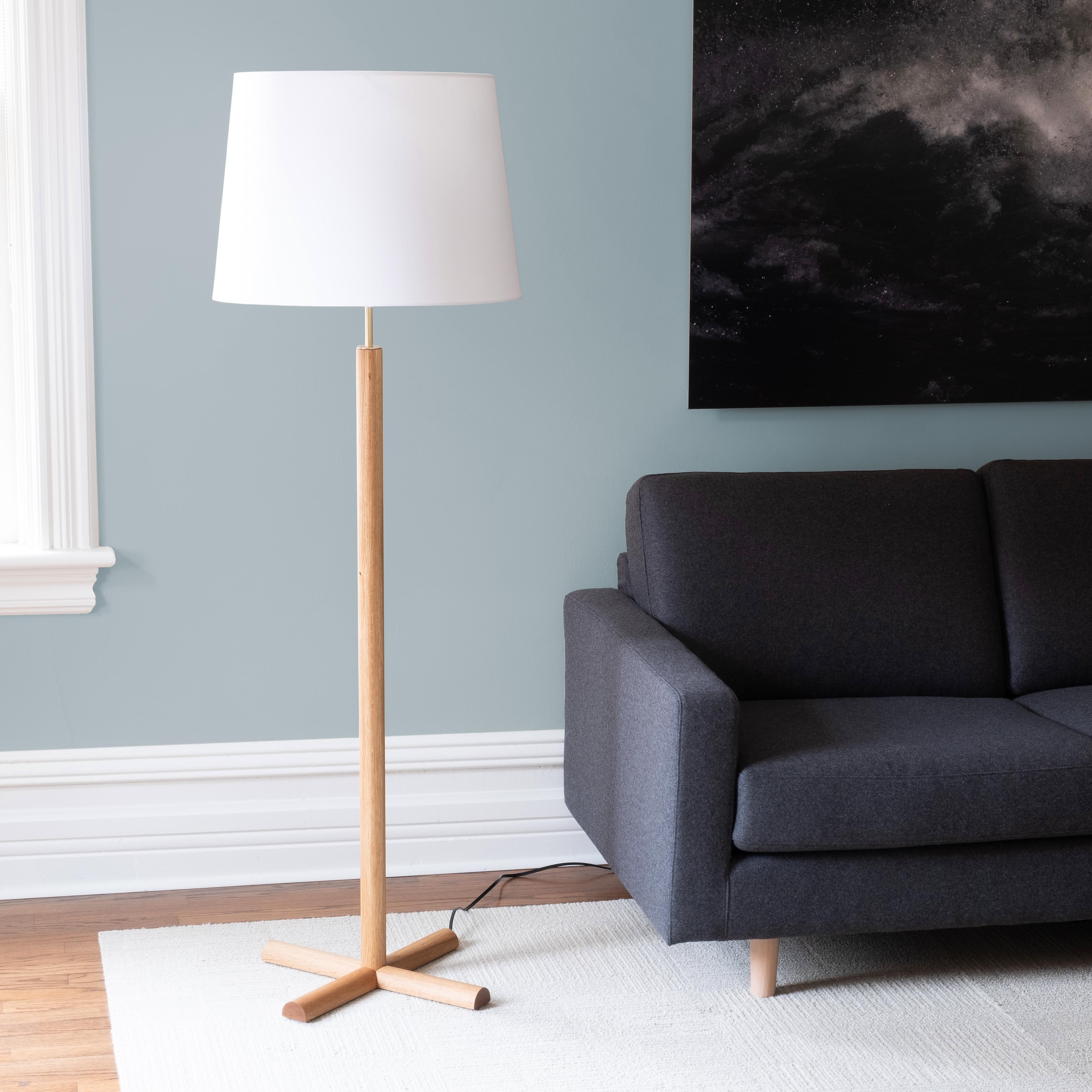 The Crux floor lamp combines minimalist forms, top-quality materials, and careful details.

The generous conical shade is supported by a clean column of turned wood, with an exposed section of brass hardware adding an elegant accent between the wood