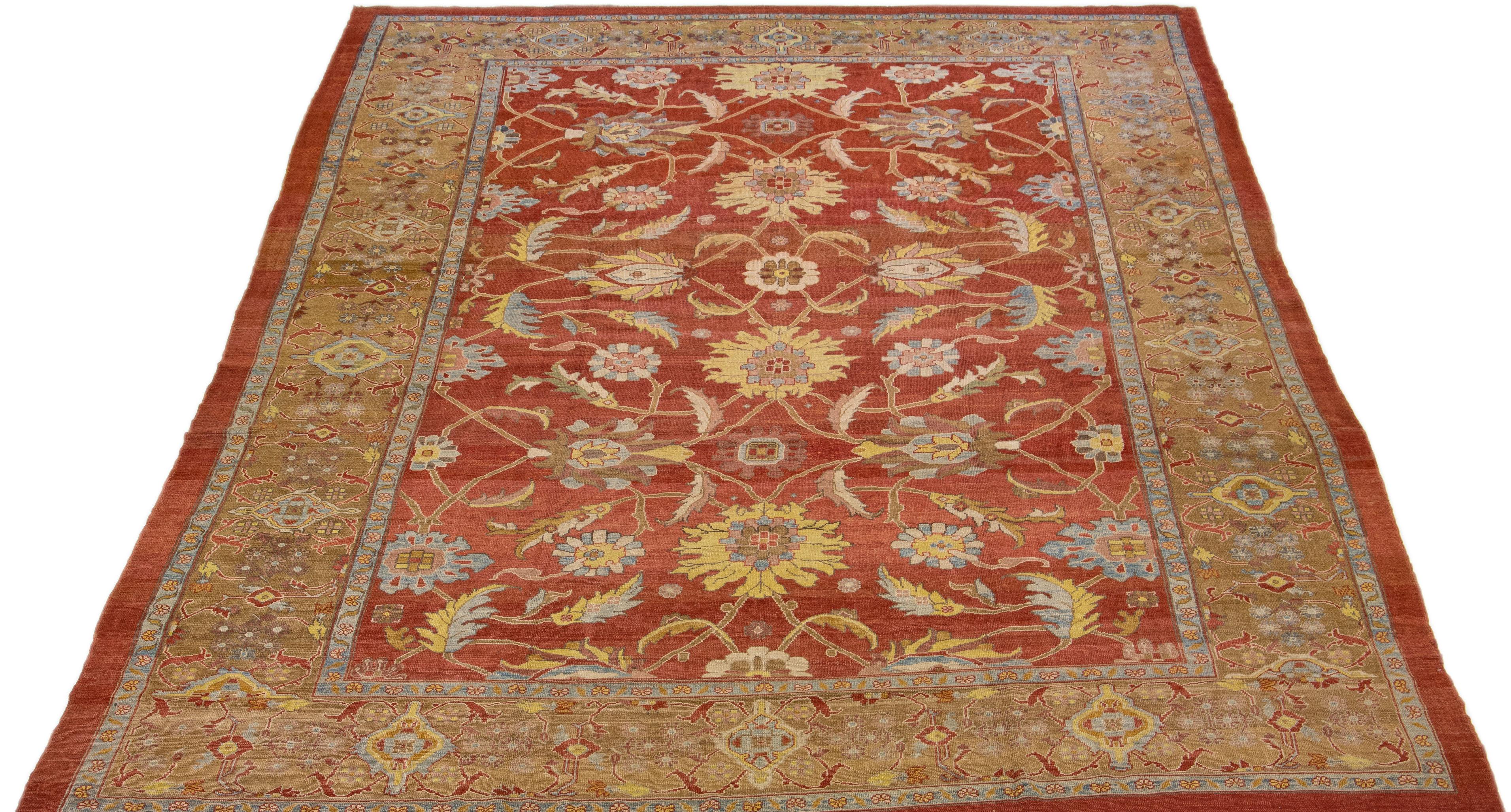 Beautiful modern Sultanabad hand-knotted wool rug with a red-rust color field. This rug has a brown designed frame with yellow, blue, and pink accents in a gorgeous all-over floral design.

This rug measures: 12'2