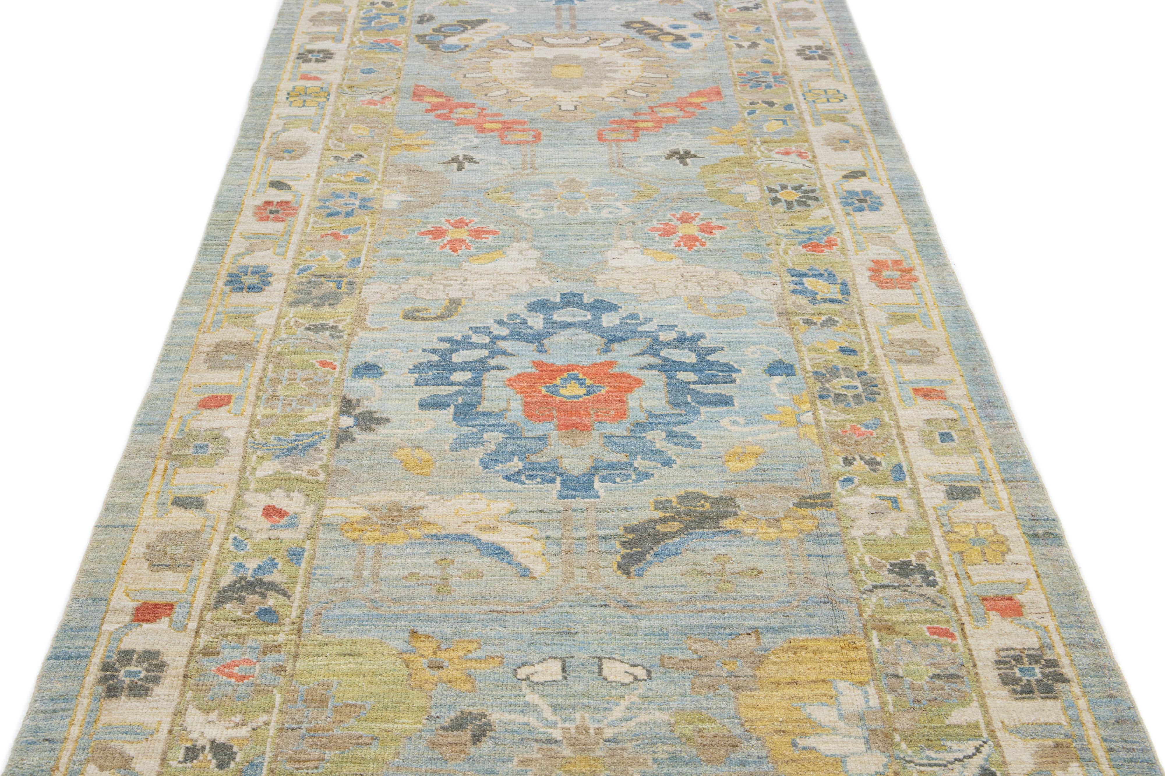 This contemporary take on the traditional Sultanabad style is showcased in an exquisite hand-knotted wool runner with a striking light blue color. An intricately designed frame accentuates its all-over floral motif, adorned with multicolored accents