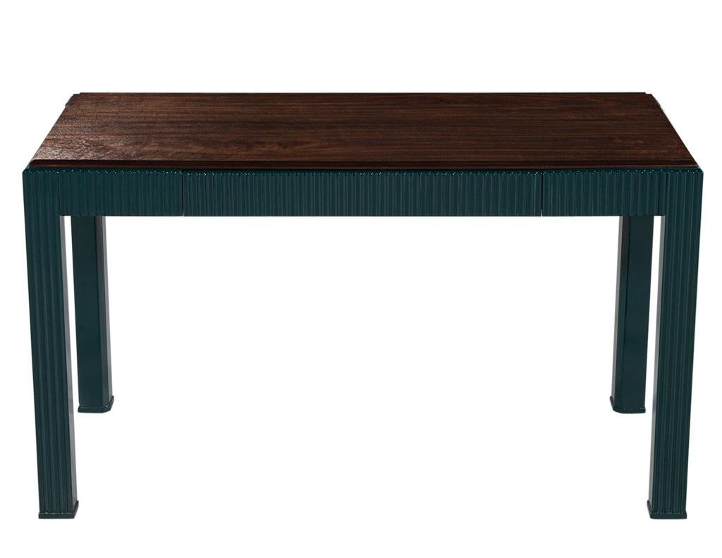 This modern fluted walnut writing desk is a beautiful piece of furniture made of walnut wood, designed with modern styling and a fluted frame finished in a turtle green color lacquer with semi-gloss sheen. The large single drawer provides plenty of