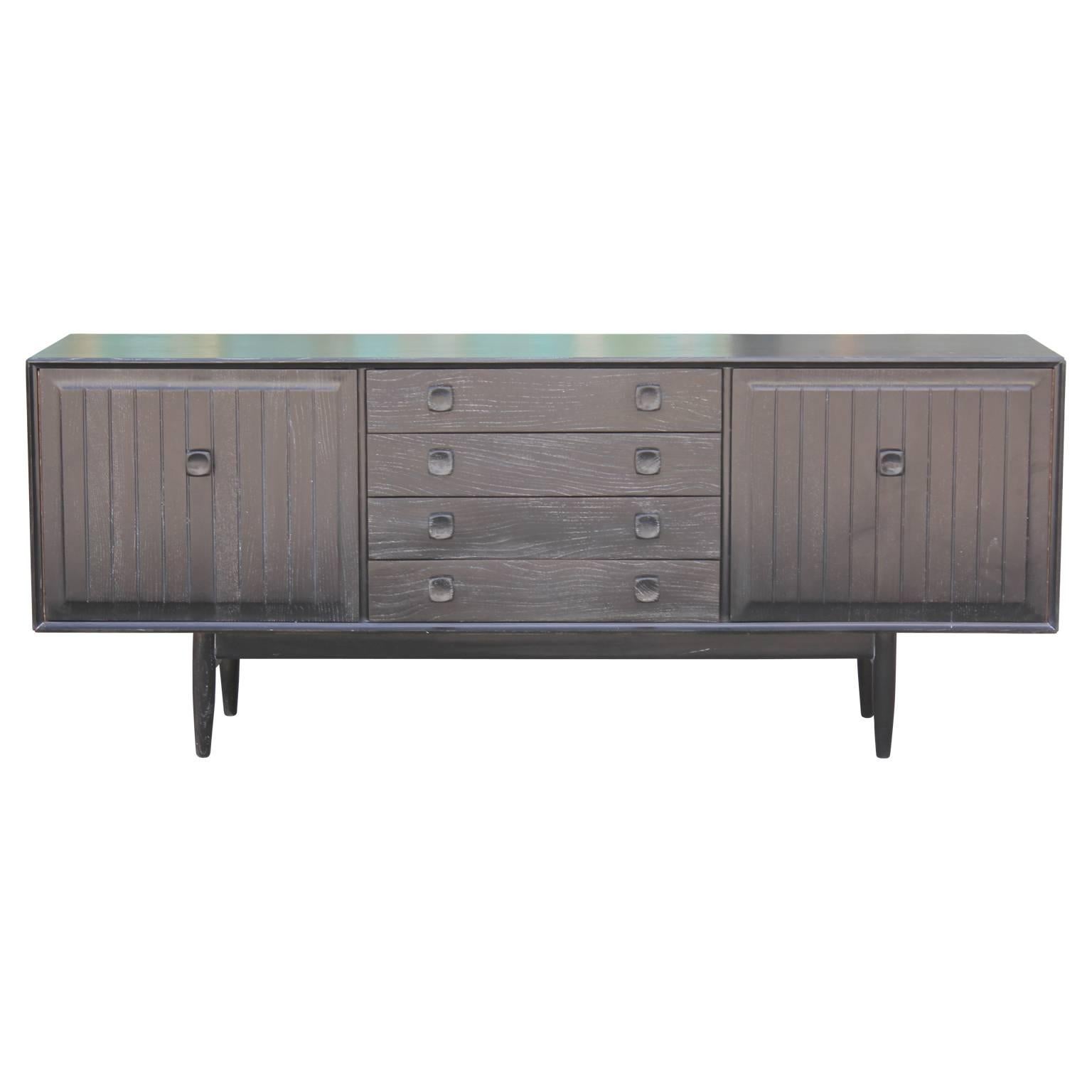 Gorgeous Mid-Century Modern credenza with a lovely cerused finish. This piece features four drawers in the centre and two cabinet spaces on either side. The cabinet on the right features a single corner shelf.