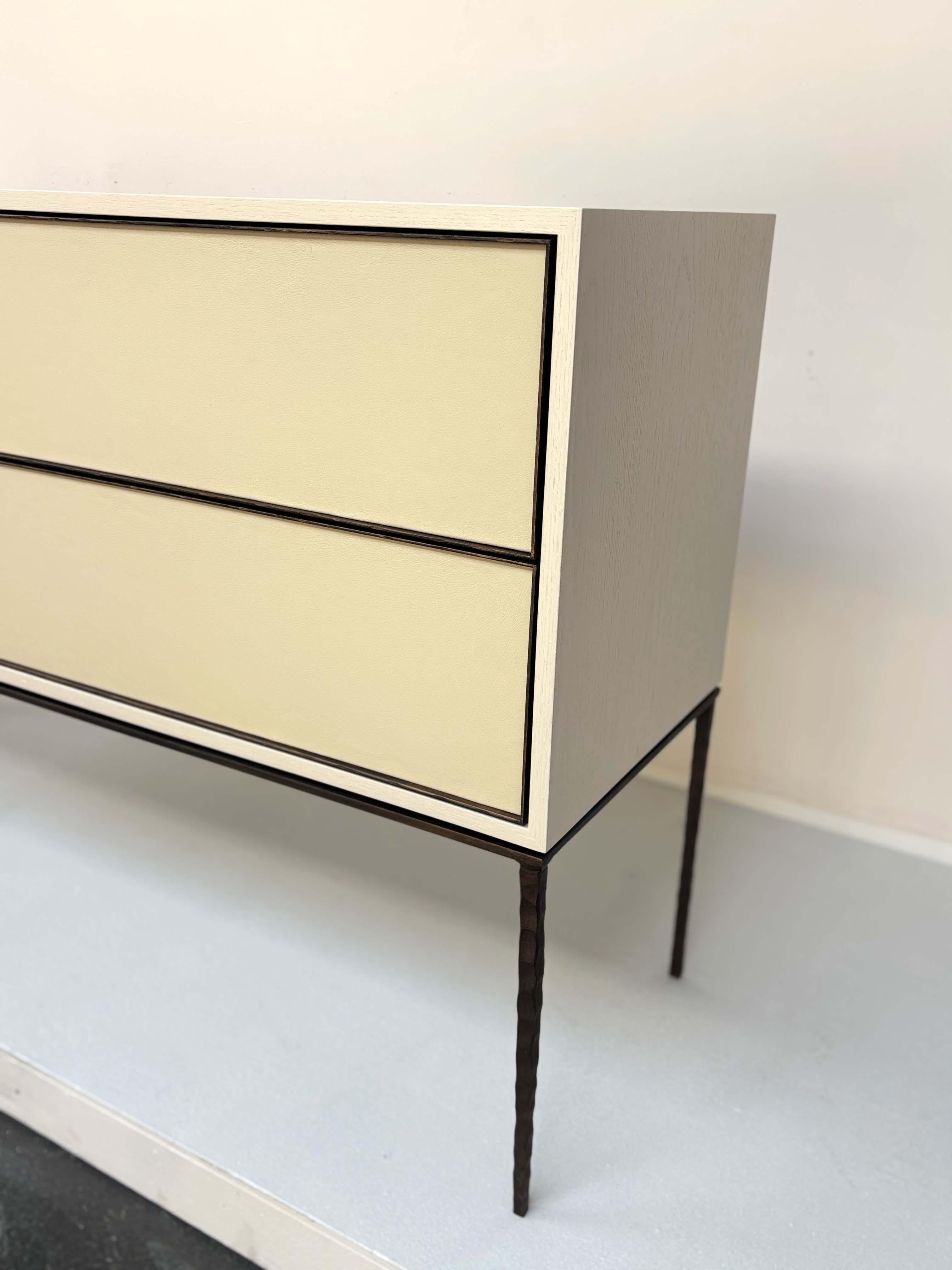 La console moderne à quatre tiroirs en cuir d'Ercole Home est un mélange raffiné de texture et d'artisanat. Construite en chêne avec une finition Sand, la console comporte des façades de tiroirs en cuir avec une fonction de fermeture tactile pour un