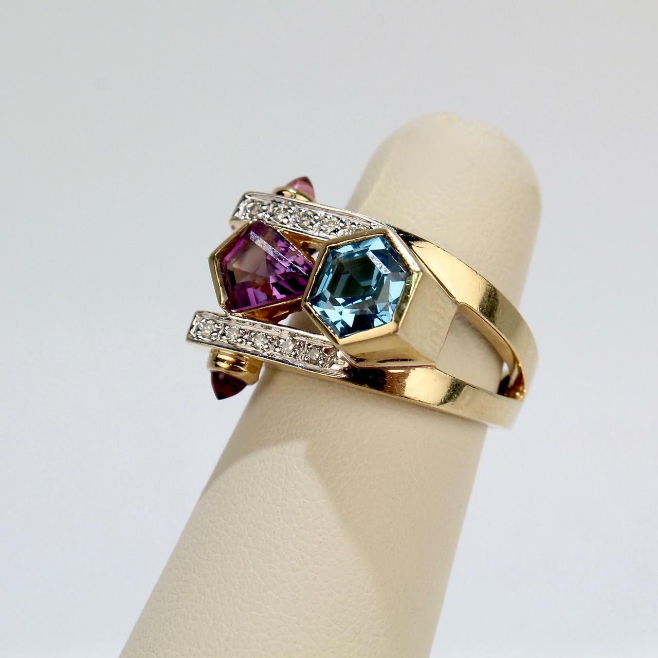 A fine modernist ring by Frank Ellman.

Having a split shank and set with a hexagonal blue topaz, a free-form amethyst, 10 accent diamonds, and flanked by 2 small amethyst cabochons. 

The shank is stamped 14K and 'Ellm' for Frank Ellman.

Ring