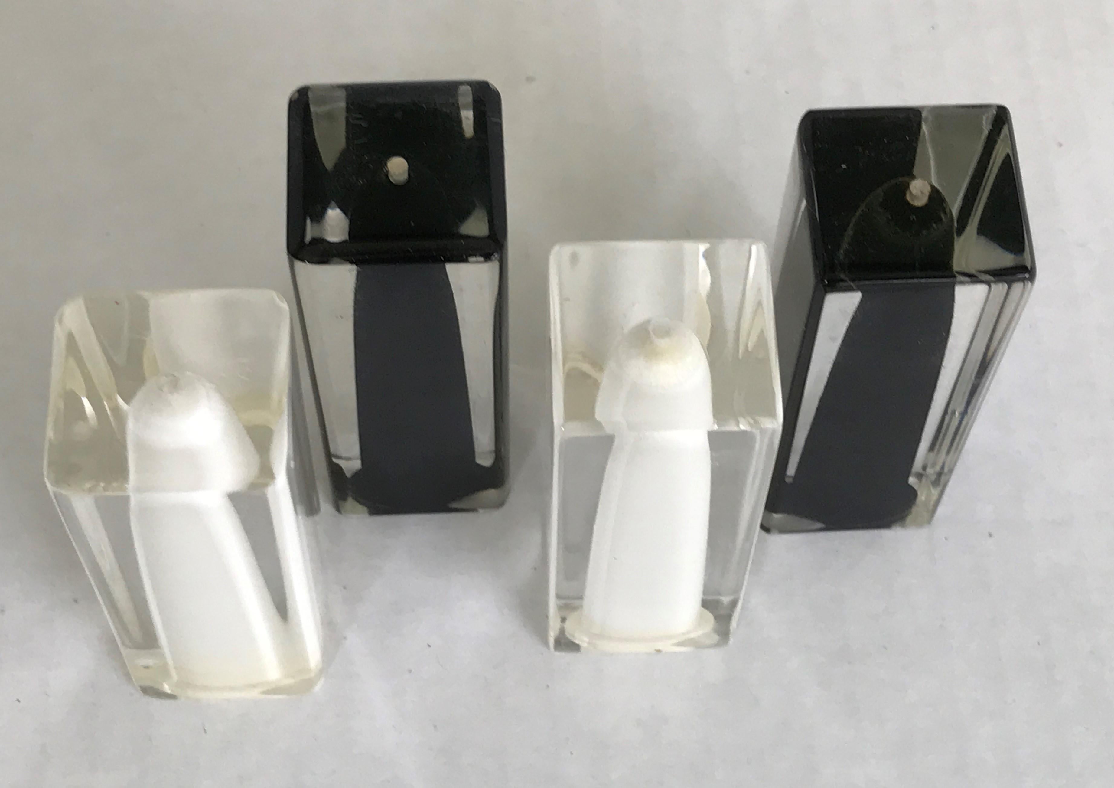Two pairs of midcentury glam thick clear Lucite with black or white insides salt and pepper shakers by Fratelli Guzzini, Italy from the 1970s. All in very good condition just minor age wear, no issues. Swanky and modern sleek. Two Salts and two