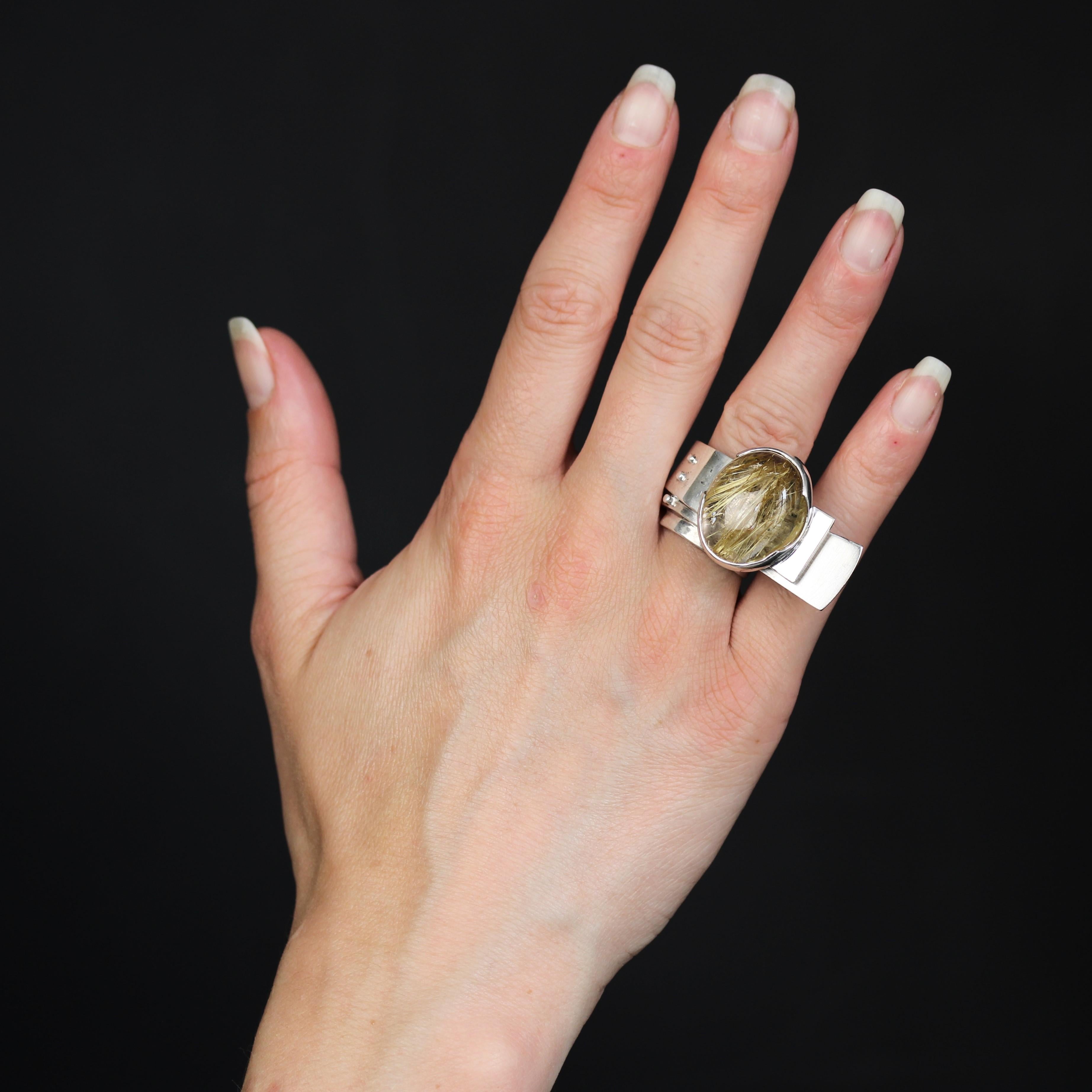 Ring in silver.
This large silver ring is formed by 2 flat ribbons that wrap around to form a ring, with asymmetrical ends. The top is set with a large cabochon dendritic quartz.
Height : 2,2 cm approximately, width : 18,8 mm approximately,