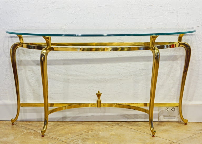 What is so striking about this solid brass demi lune console table is the fusion of traditional cabriole legs and a perfectly modern design. The table is more slender (elongated) than ordinary demi lune tables providing a combination of great width