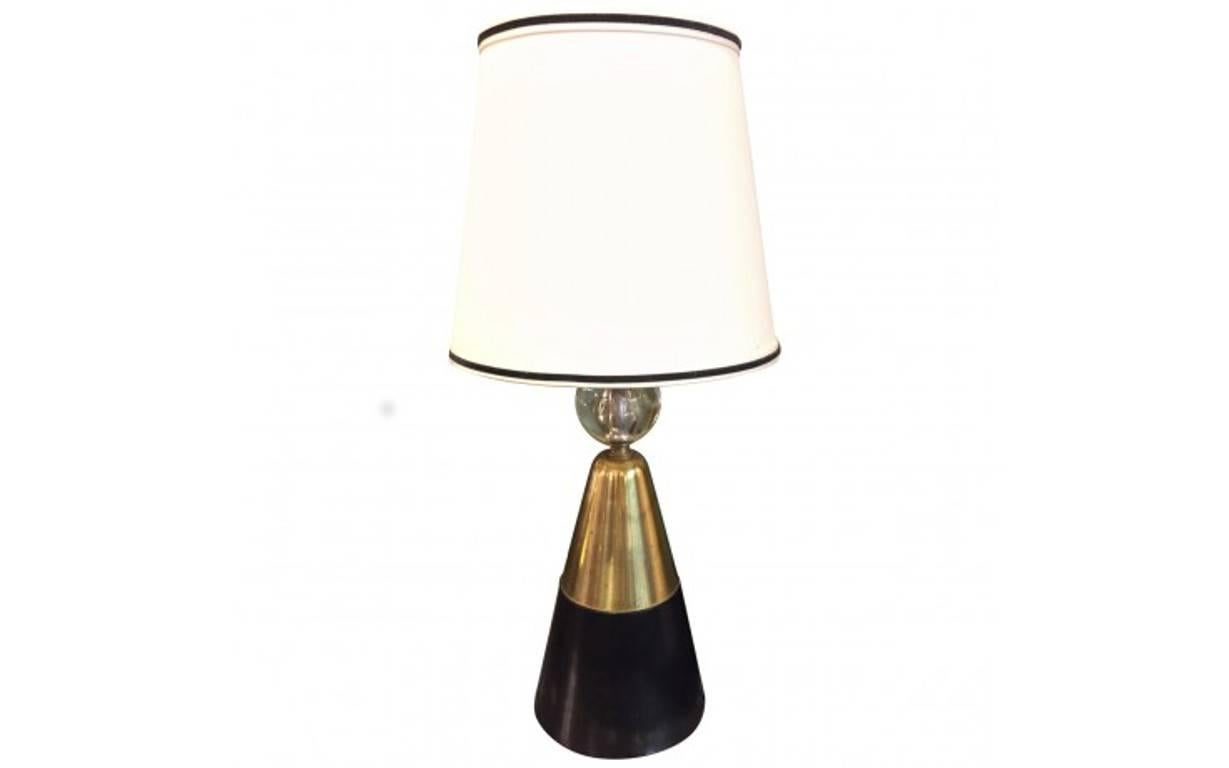 The cone-shaped bases of these modern table lamps combine dark-stained wood and brass, ending in a simple glass orb. They are topped with a white linen shade with a black velvet accent for a clean and stylish colorblocked look. Sold as a set of two.