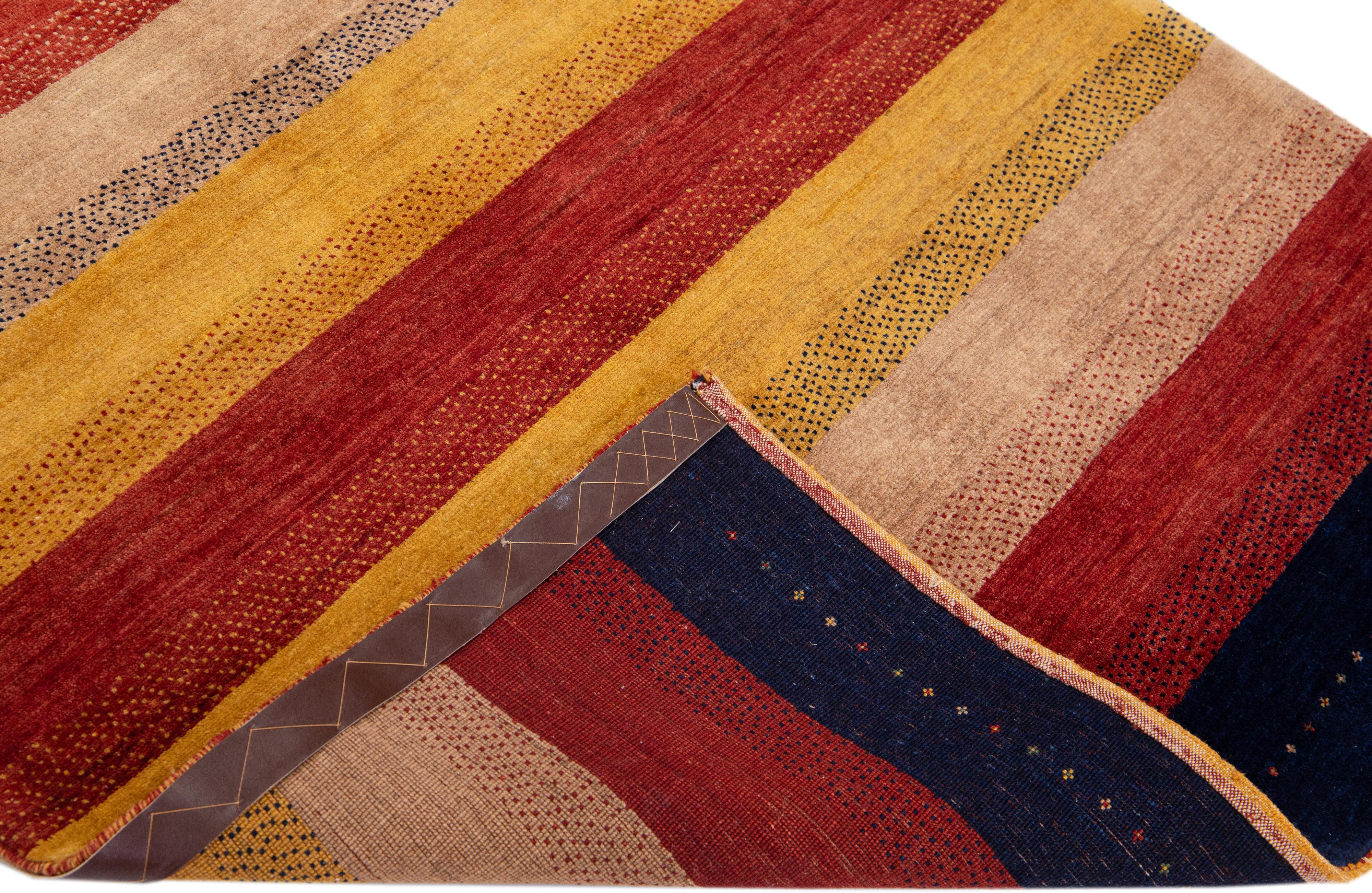 Beautiful modern Persian Gabbeh hand-knotted wool rug with a red, yellow, and brown field. This Gabbeh rug has a gorgeous stripe design.

This rug measures: 3'10