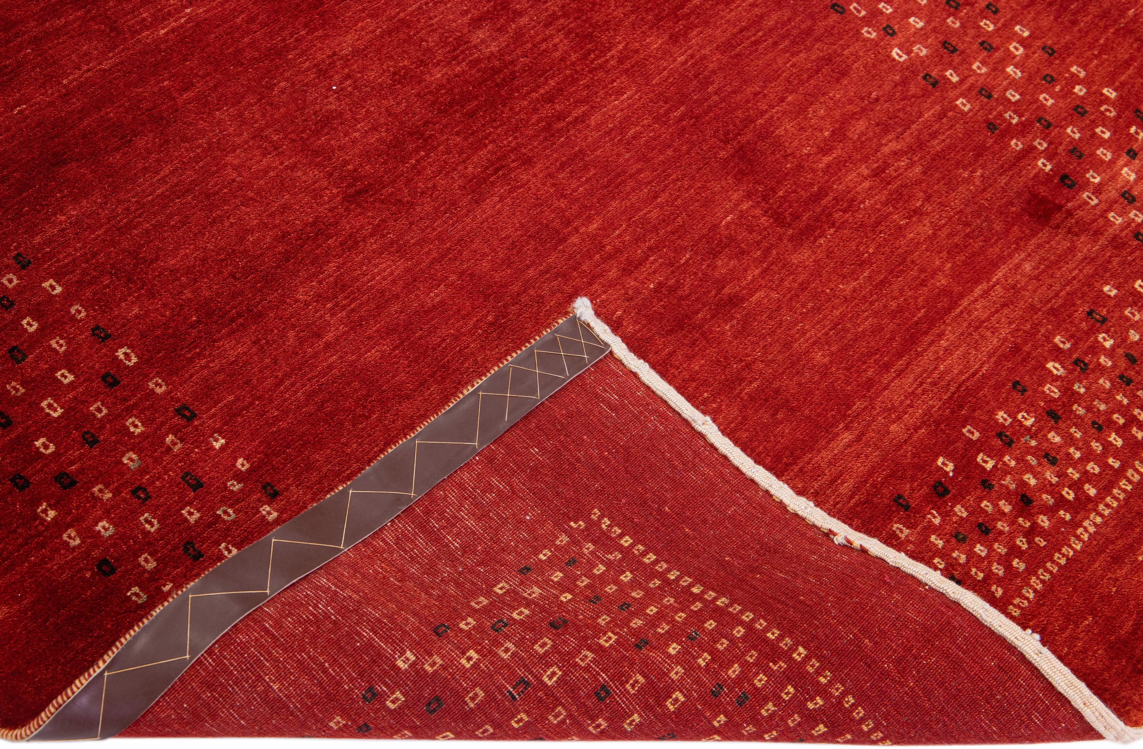 Beautiful modern Gabbeh hand-knotted wool rug with a red field. This Persian rug has beige and black accents in a gorgeously minimalist design.

This rug measures: 4' x 6'.

Our rugs are professional cleaning before shipping.