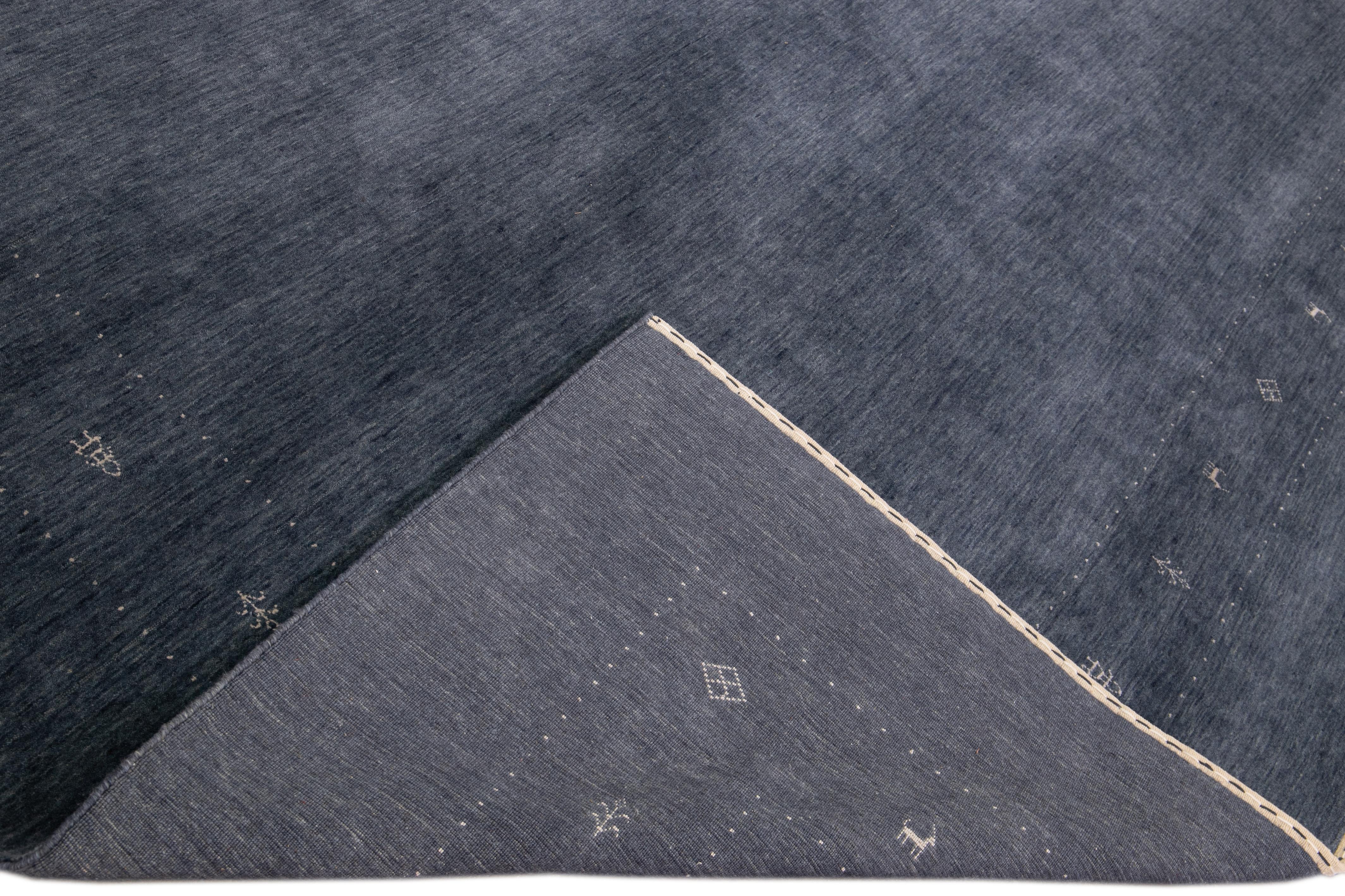 Schöner moderner Gabbeh-Stil Hand-Loom Wollteppich mit einem blauen Feld. Dieser Teppich im Gabbeh-Stil hat weiße Akzente in einem herrlichen geometrischen Minimal-Design.

Dieser Teppich misst: 12' x 15'.

Unsere Teppiche werden vor dem Versand