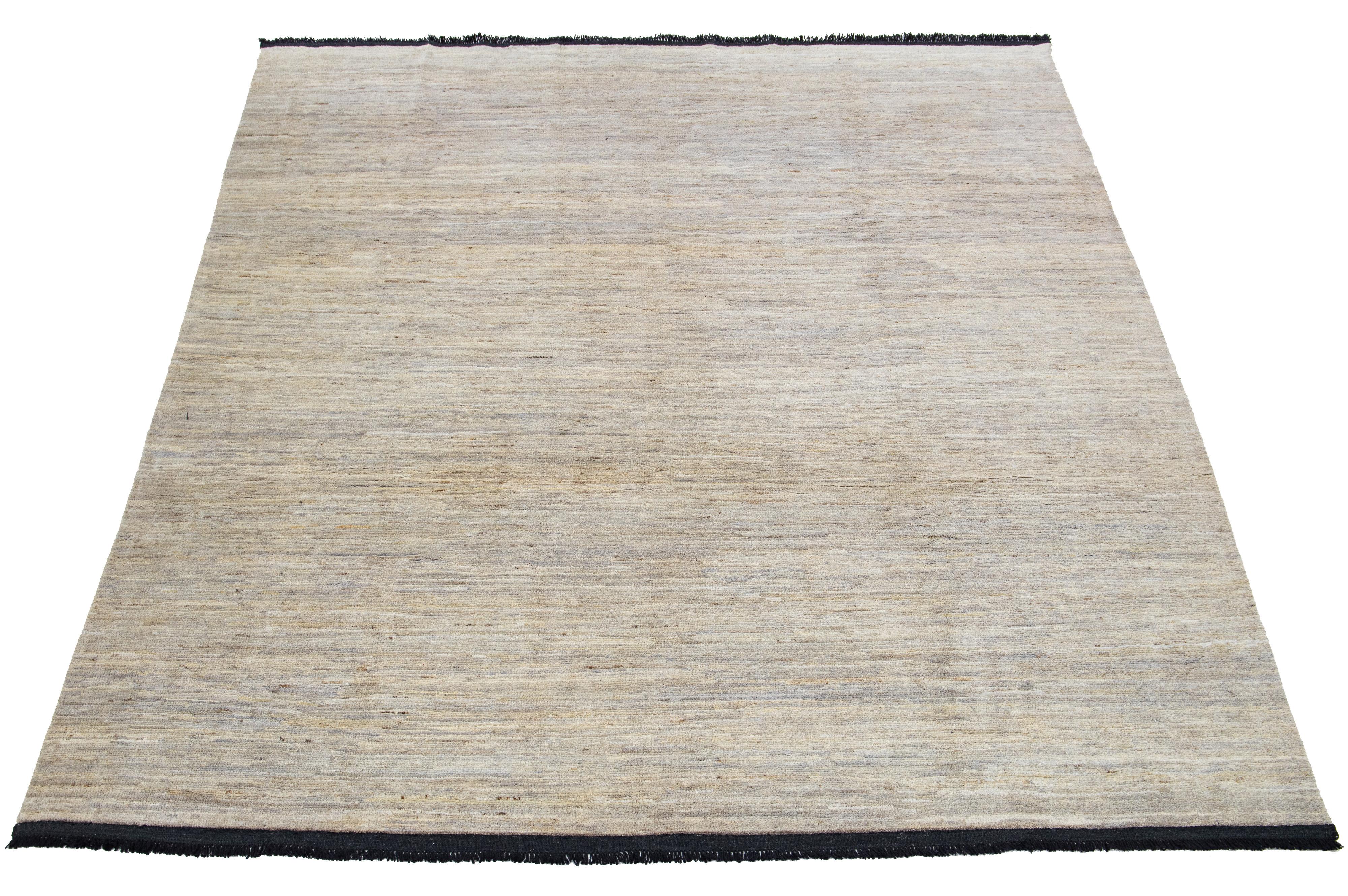 This handcrafted wool rug, designed in the Gabbeh style, showcases a solid design accentuated by gray shades against a beige background with black fringes.

This rug measures 8' x 10'.

Our rugs are professionally cleaned before shipping.