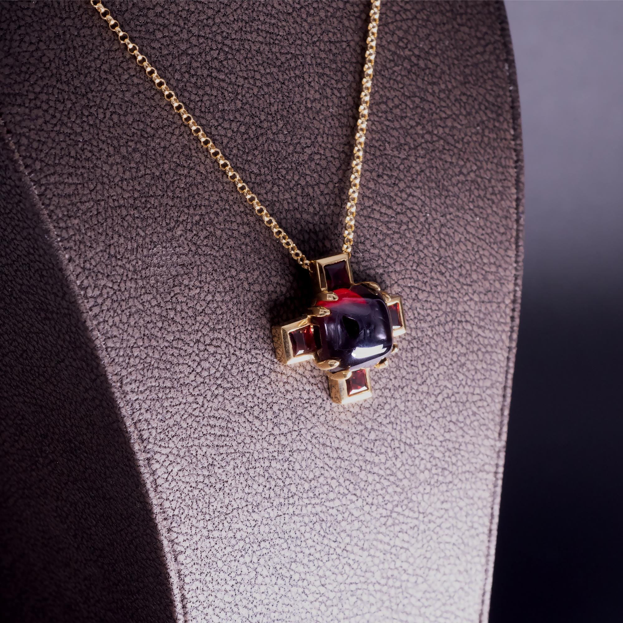Very fashionnable, modern looking pendant necklace. A nice chubby sugarloaf cabochon garnet in it center, while four princess cut garnets makes the branches of the cross.

