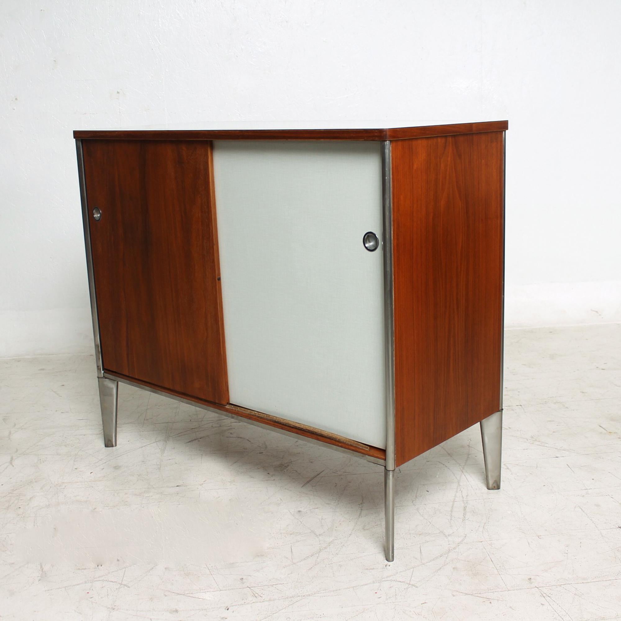 Cabinet
Modern Industrial Storage Cabinet by Industrial designer Raymond Loewy for Hill-Rom Company USA 1950s
 34tall x 39.5 W x 17.5 inches
Walnut Plywood on Sculptural Tapered Stainless-Steel legs. Formica Laminate Top is Light Gray with grid