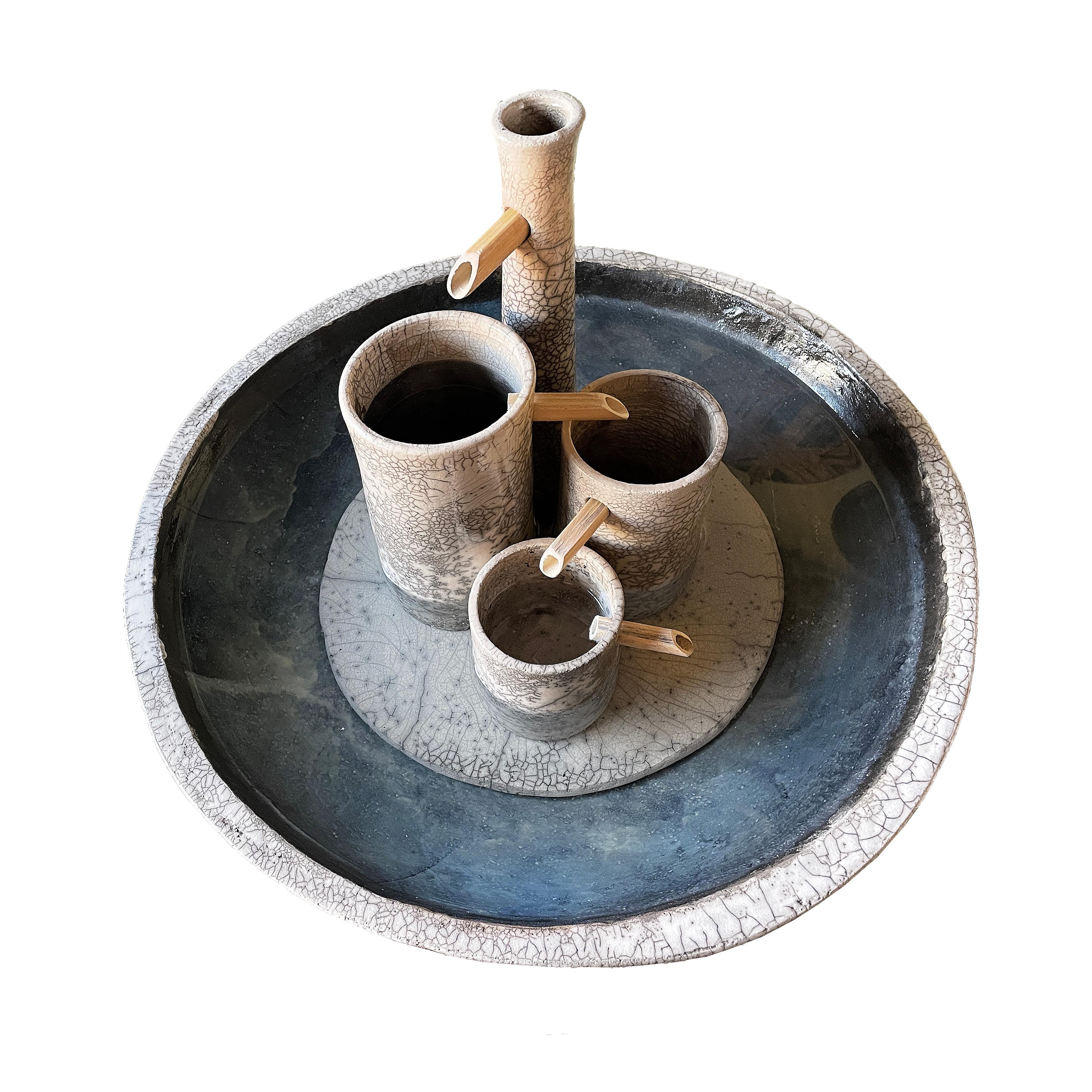 La plus élégante des fontaines de Genesi, c'est un plaisir pour les yeux et pour les oreilles. Les éléments en raku laissent l'eau s'écouler perpétuellement du plus grand au plus petit récipient et finalement dans le grand récipient, créant un son