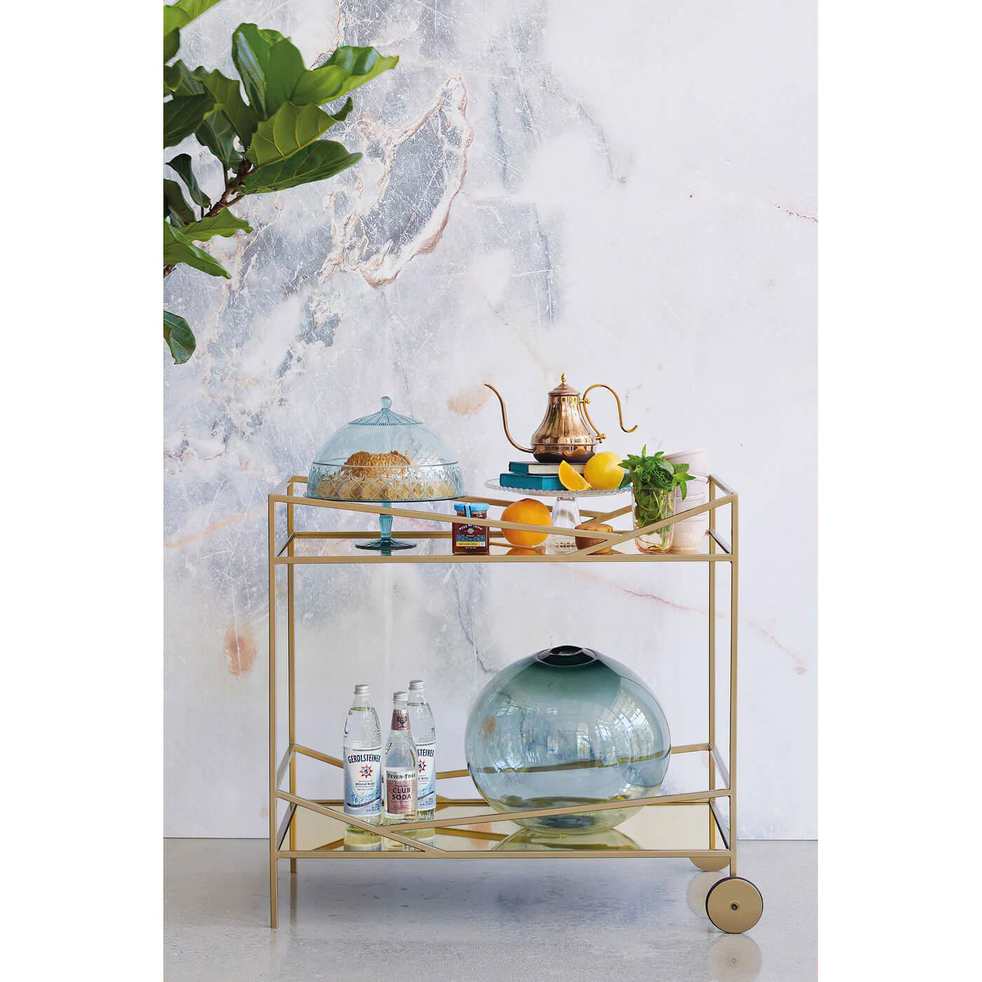 A modern geometric bar cart with an open framework design. Its architectural-inspired metal supports give this piece its modern character while the warm Lucent Bronze finish ensures it will complement any decor plan. Two bronze mirrored shelves are