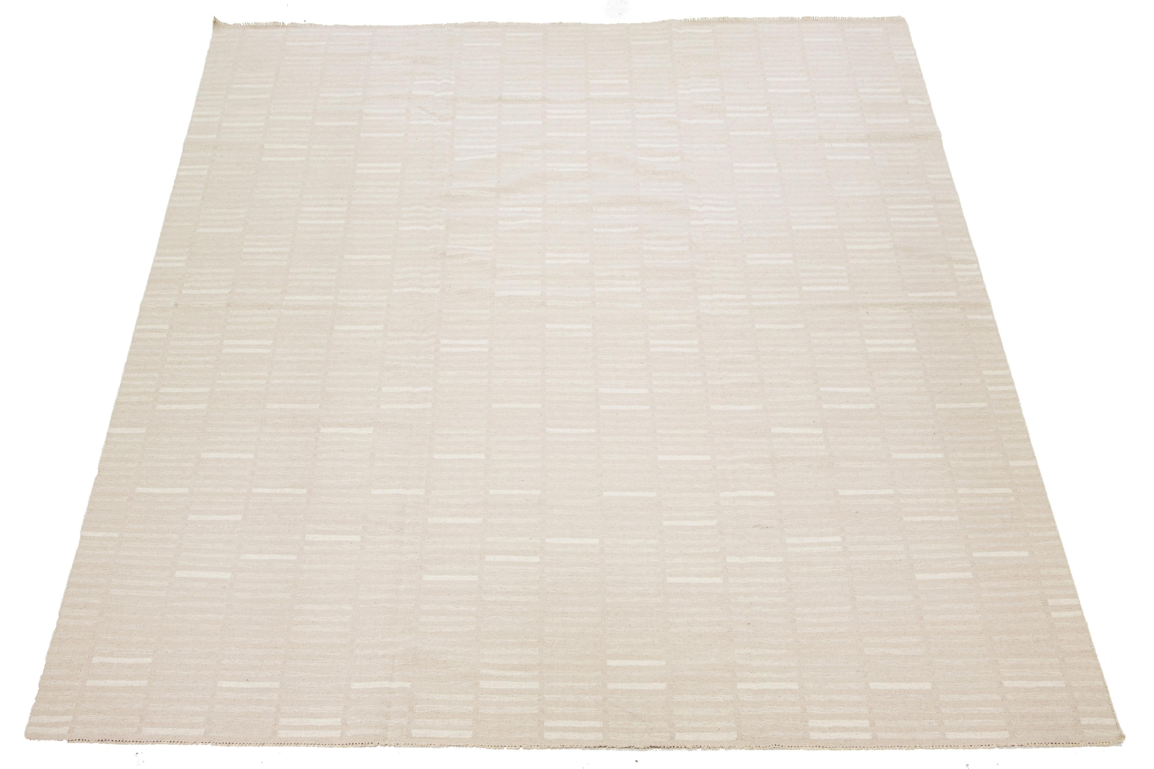 Questo tappeto presenta un design organico e moderno caratterizzato da un intreccio piatto in lana Rug & Kilim. Presenta un motivo geometrico nei toni del beige e dell'avorio, che lo rende un'aggiunta elegante agli spazi contemporanei.

Questo