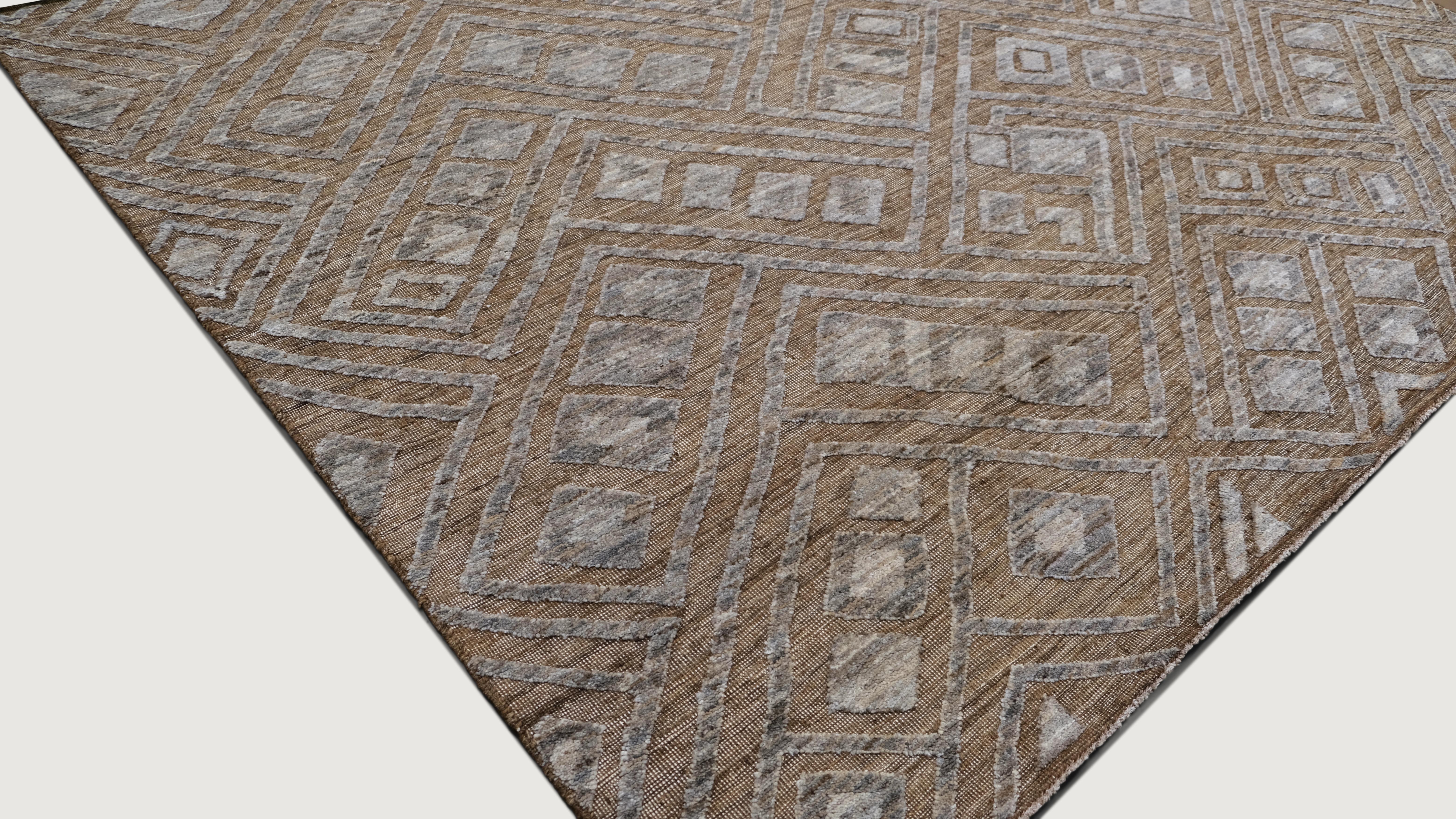 Ce tapis en laine noué à la main présente un étonnant design tribal géométrique avec des motifs de diamants complexes dans des tons chauds et terreux de brun, gris et ivoire. Les variations de tons et la texture à poils ras créent une profondeur