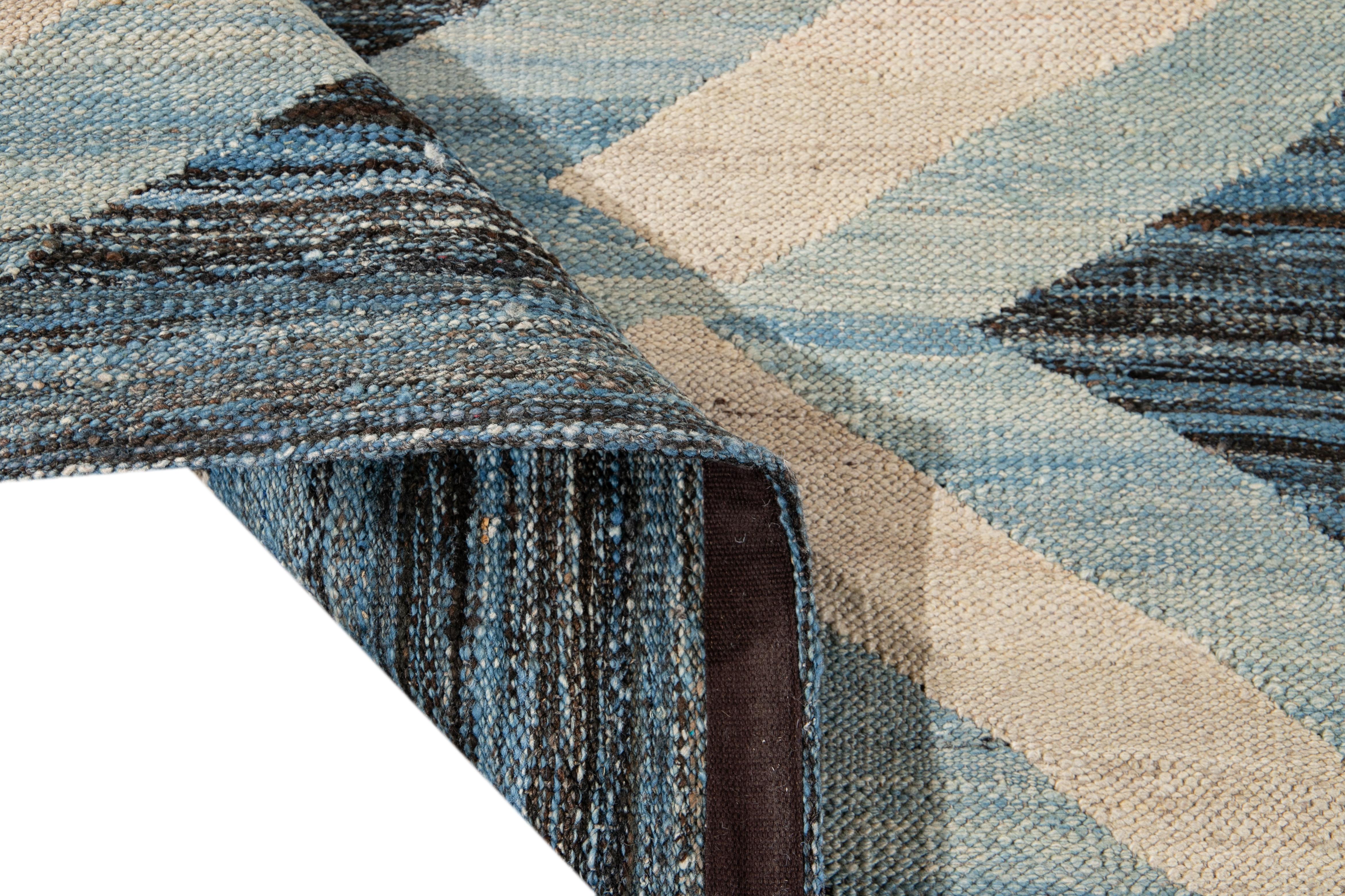 Preciosa alfombra moderna de lana Kilim de tejido plano, hecha a mano, con un campo abstracto marrón y azul. Esta alfombra kilim tiene toques de marfil y azul claro en un precioso diseño geométrico.

Esta alfombra mide 8'6
