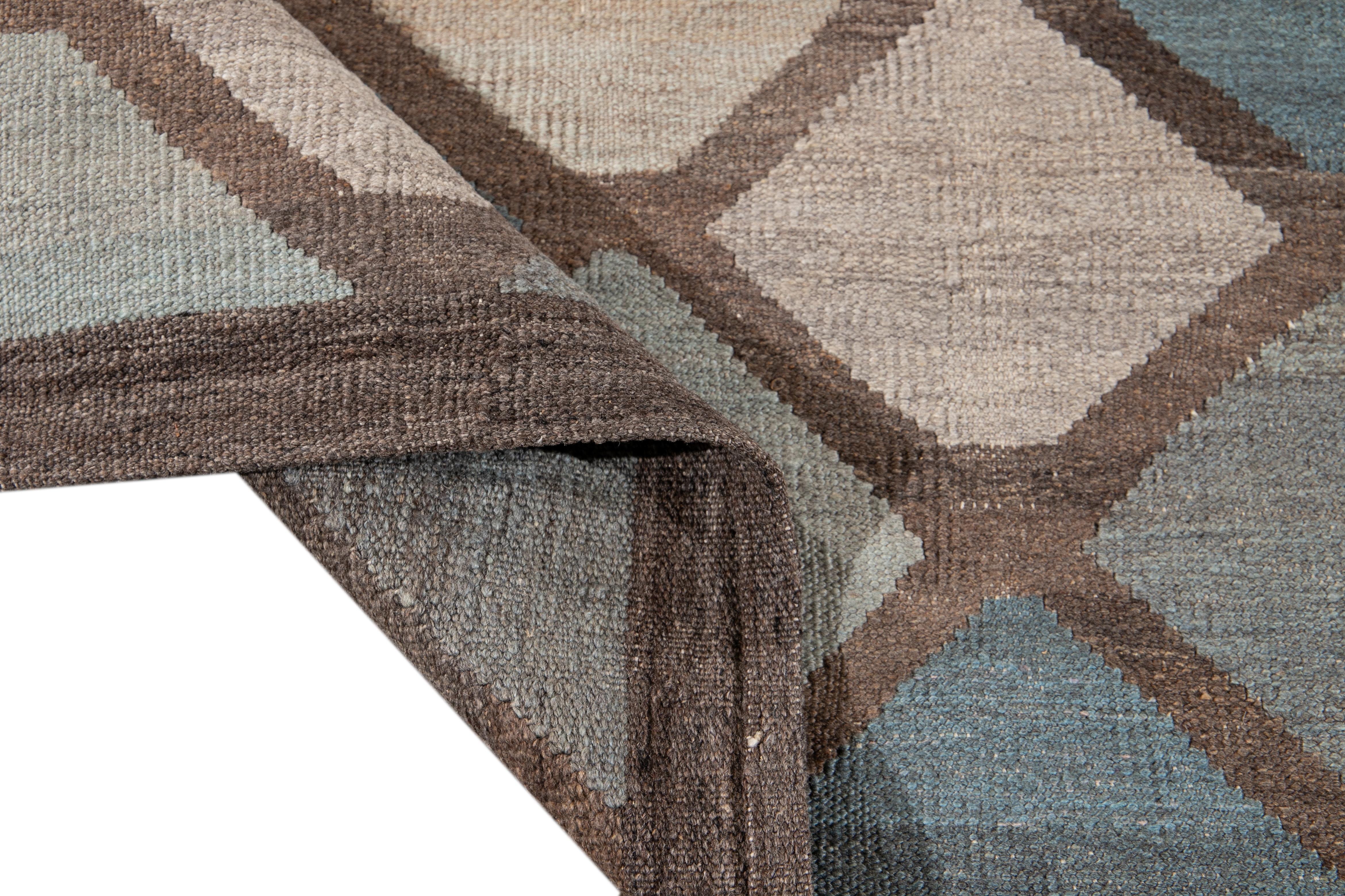 Schöner moderner flachgewebter Kilim-Teppich aus handgefertigter Wolle. Dieser Kilim-Teppich hat ein Feld aus Blau, Braun und Beige in einem wunderschönen geometrischen Muster.

Dieser Teppich misst: 8'1